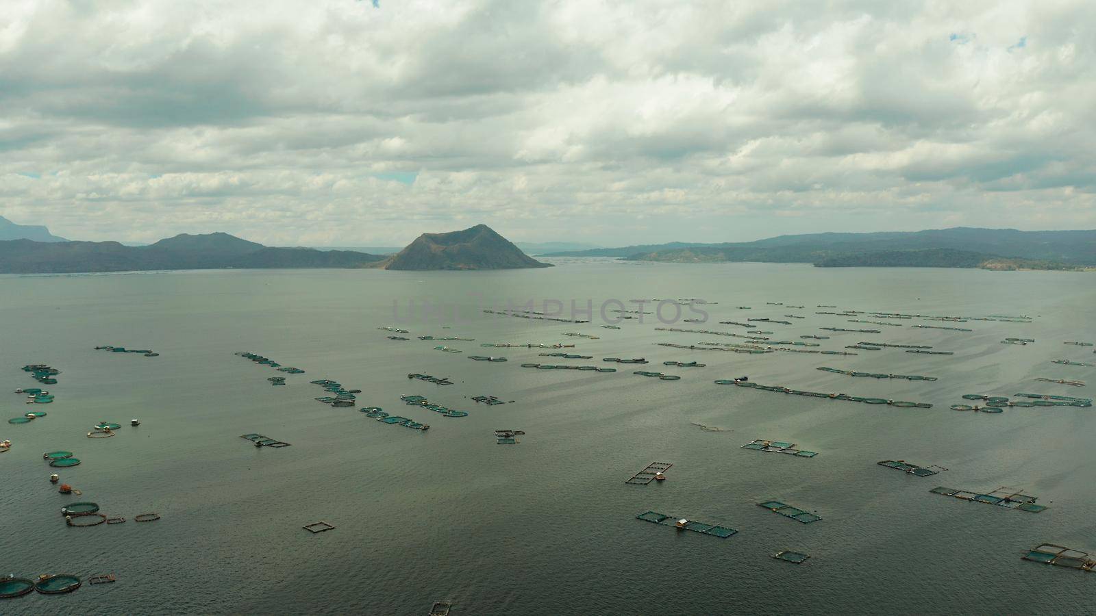 Taal volcano on an island in middle lake with fish farm, aerial view. Luzon, Philippines Tropical landscape, mountains and volcano in the lake.