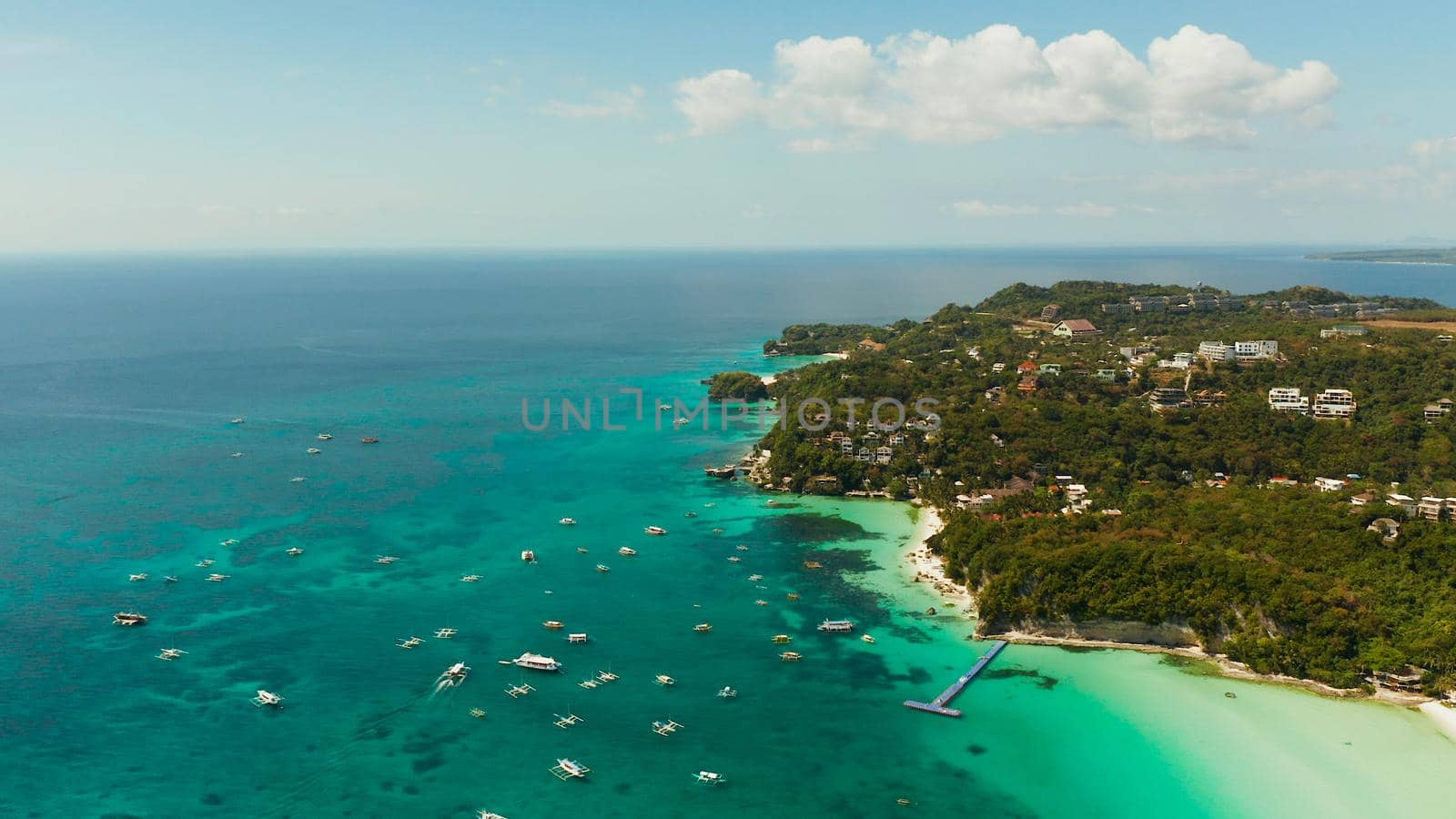 Sandy beach and turquoise water in the tropical resort of Boracay, Philippines. White beach with tourists and hotels. Summer and travel vacation concept.