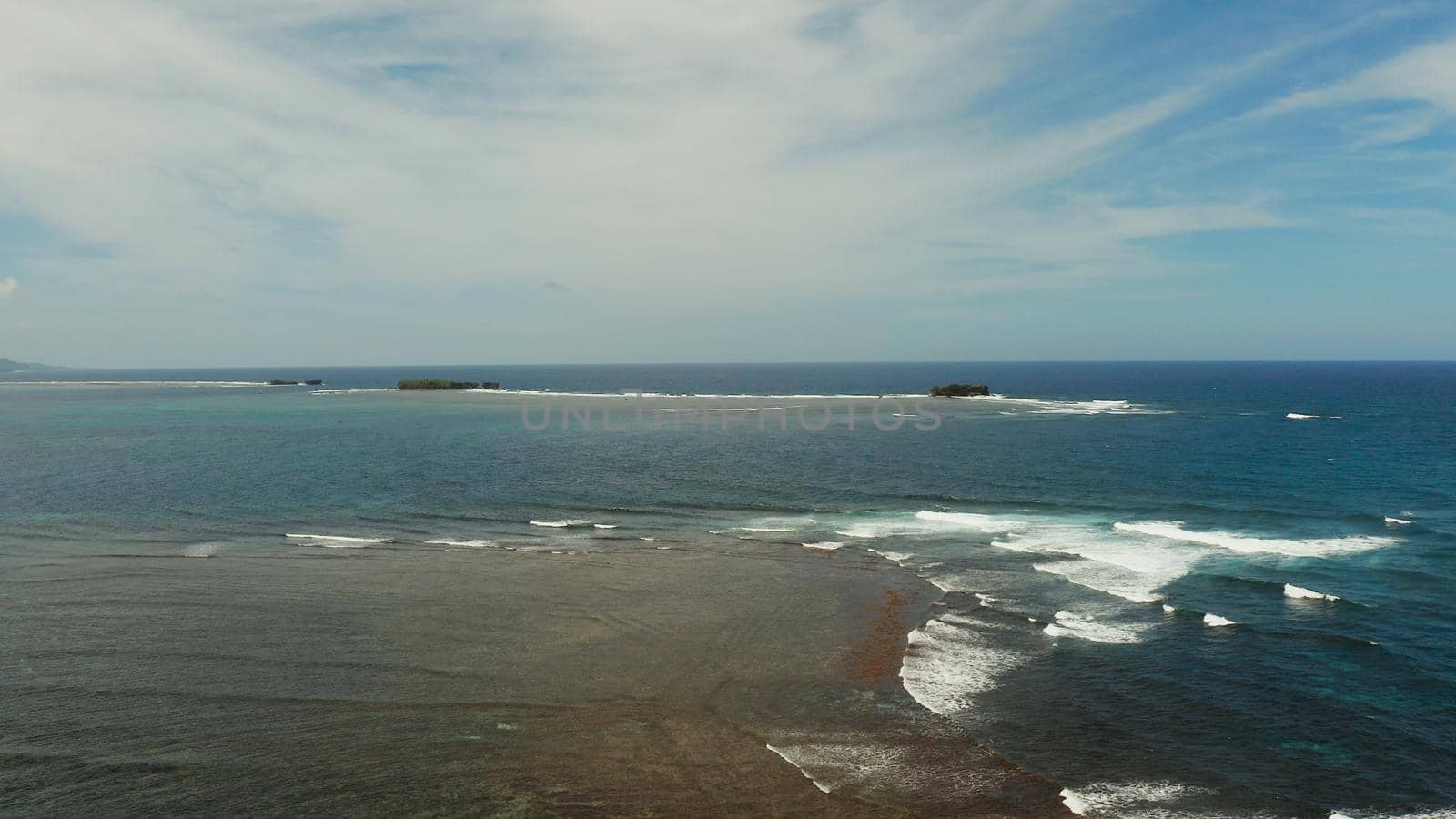 Aerial view of tropical islands in the ocean with waves crashing on the shore, top view. Siargao, Philippines. Summer and travel vacation concept.