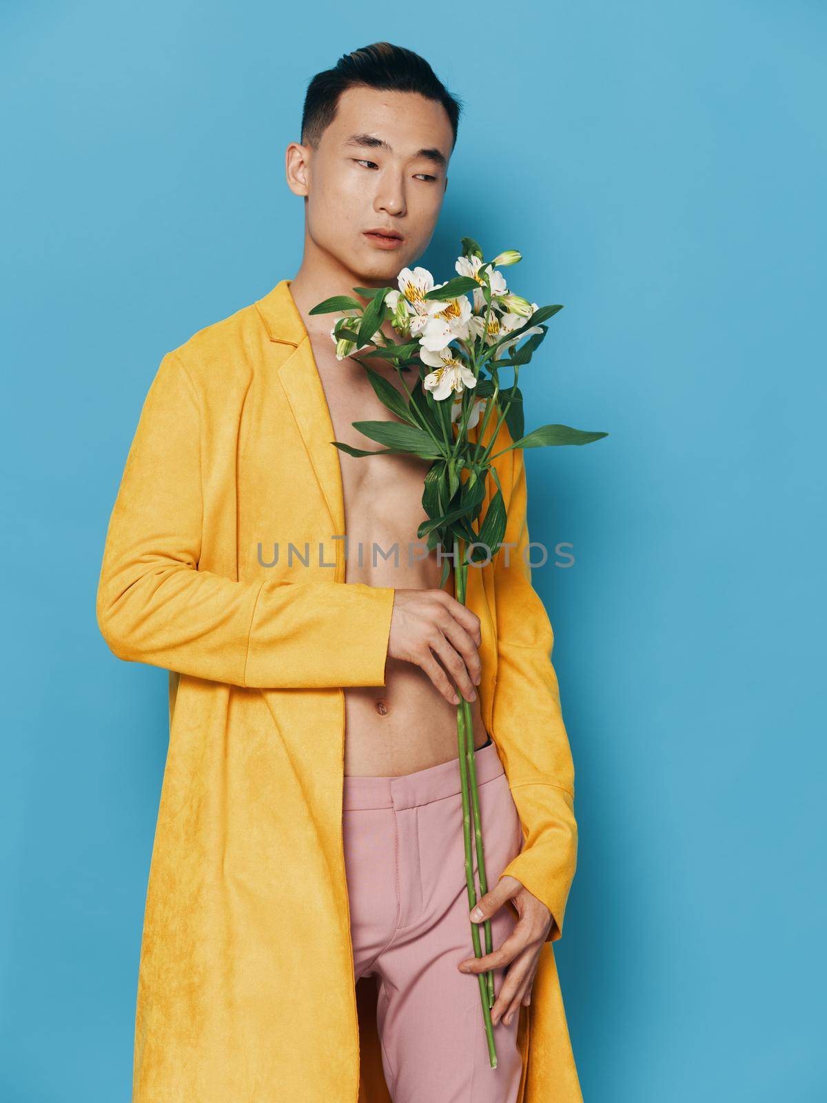 male korean appearance with a bouquet of flowers in a yellow coat and pink trousers. High quality photo