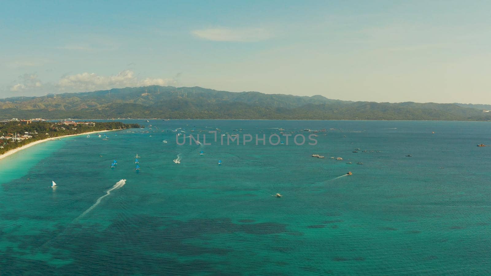 Tropical lagoon with turquoise water, sailing yachts and white sand beach from above. Boracay, Philippines. White beach with tourists and hotels. Summer and travel vacation concept.