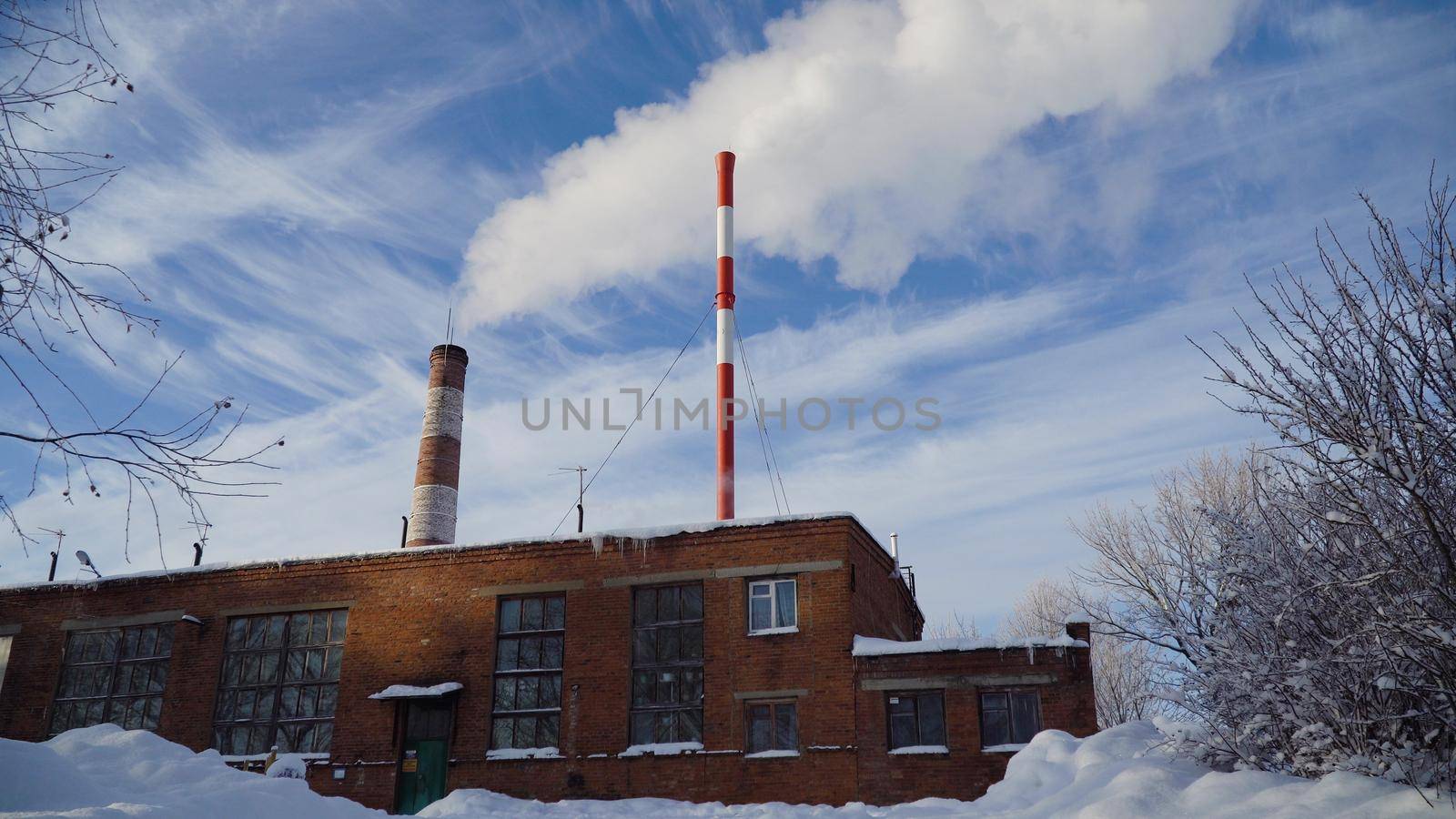 Boiler room in the winter season, from the chimneys rise up clouds of steam. Pipes of a thermal power plant. Boiler house, pipe plant, boiler plant.