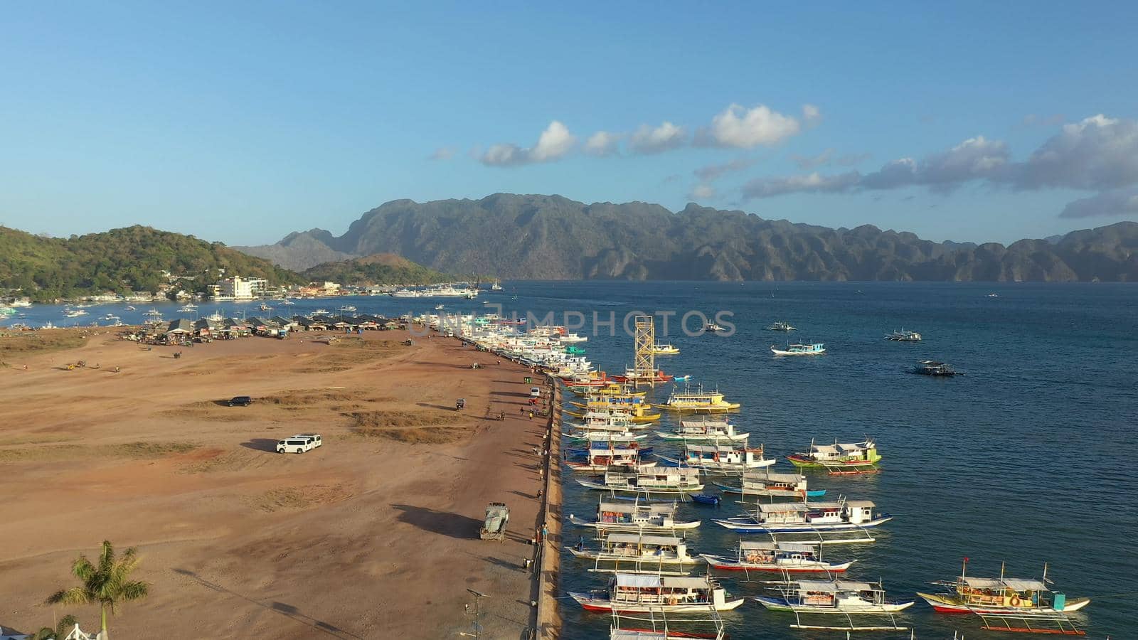 aerial view Pier and promenade Coron town with boats on Busuanga island. Wooden boats waiting at pier. Seascape with mountains. Philippines, Palawan