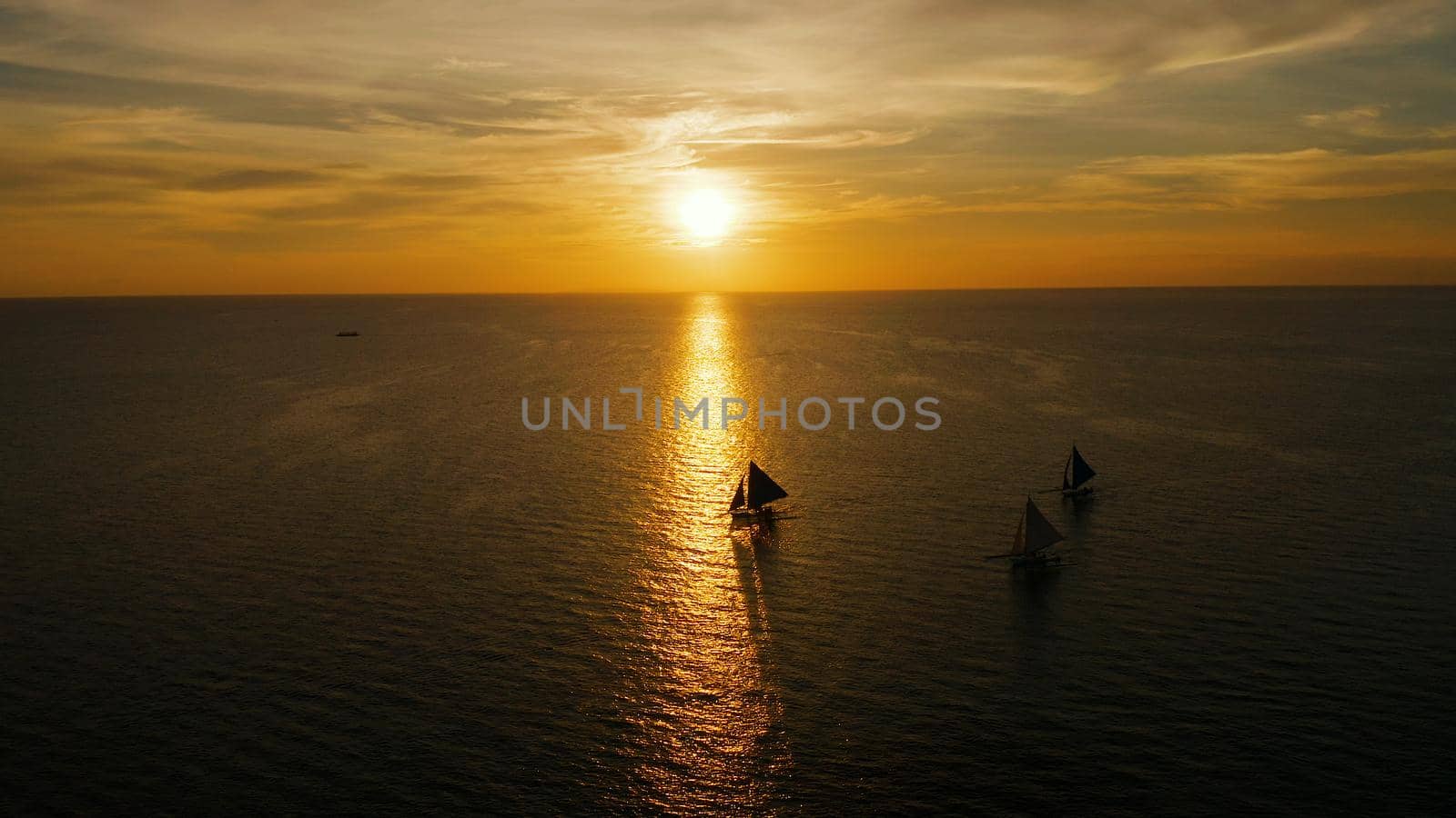 Sunset above the sea surface with sail boats, aerial view Boracay, Philippines. Reflected sun on a water surface. Sunset over ocean. Seascape, Summer and travel vacation concept