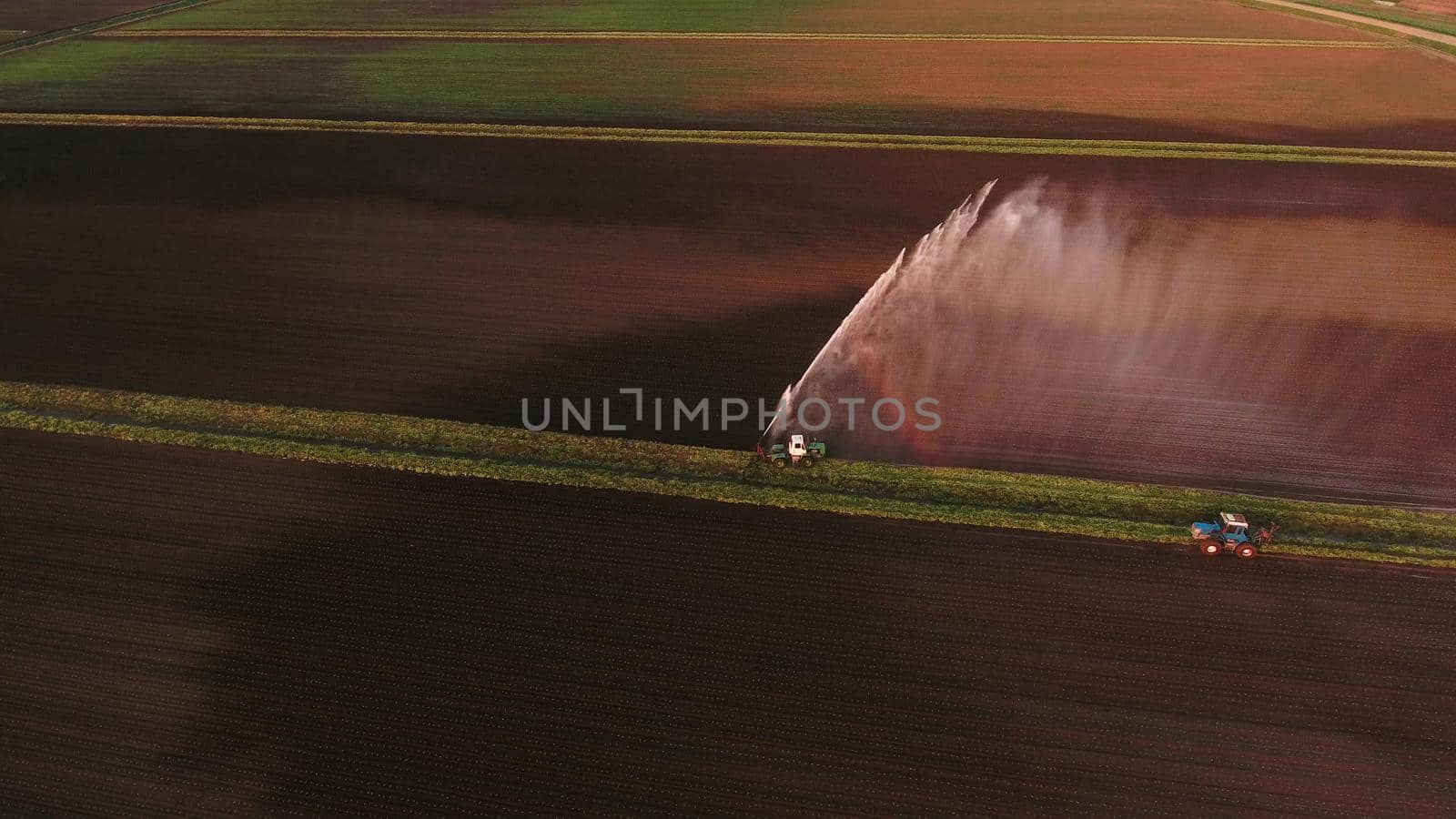 Irrigation equipment watering freshly seeded field.Irrigation at sunset.Irrigation of farmland to ensure the quality of the crop. Aerial view:irrigation system watering a farm field.