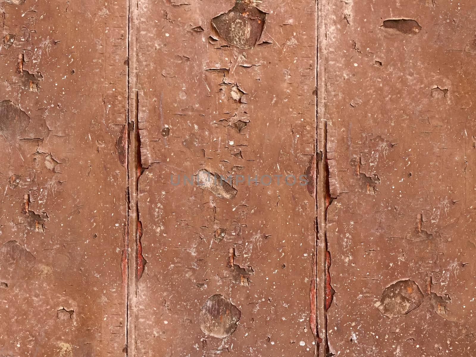 Old exfoliating brown paint from the wood surface of the board close-up.Texture or background