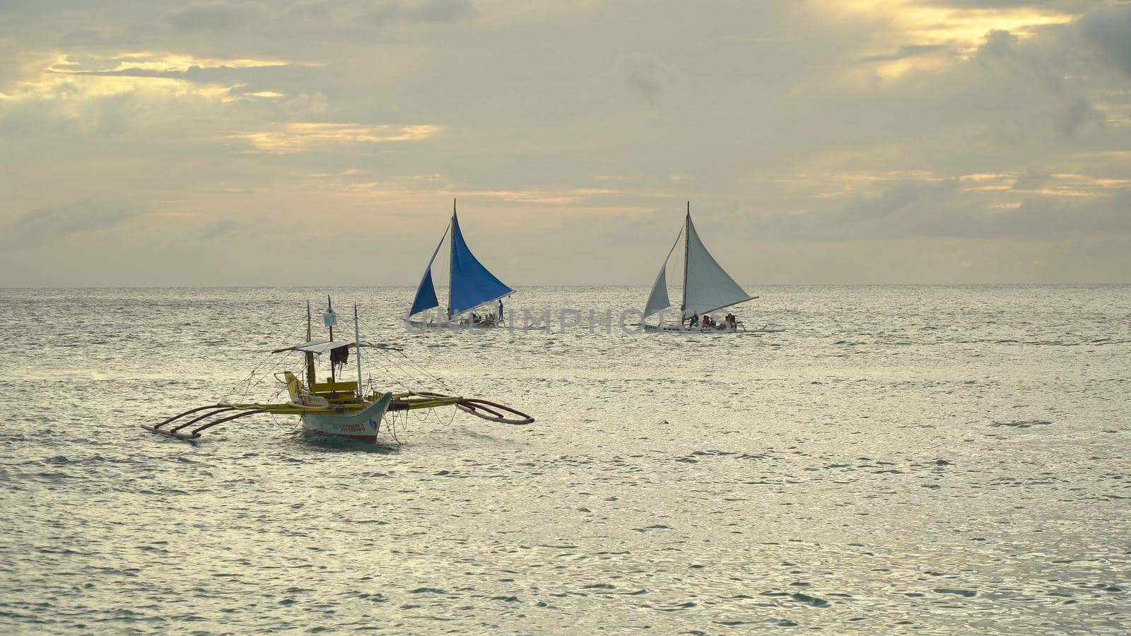 Sailing ship yachts with blue sails in the ocean at the sunset. Sailing boat on sea. Sailing ship yachts in the sea. Philippines, Boracay. Travel concept.