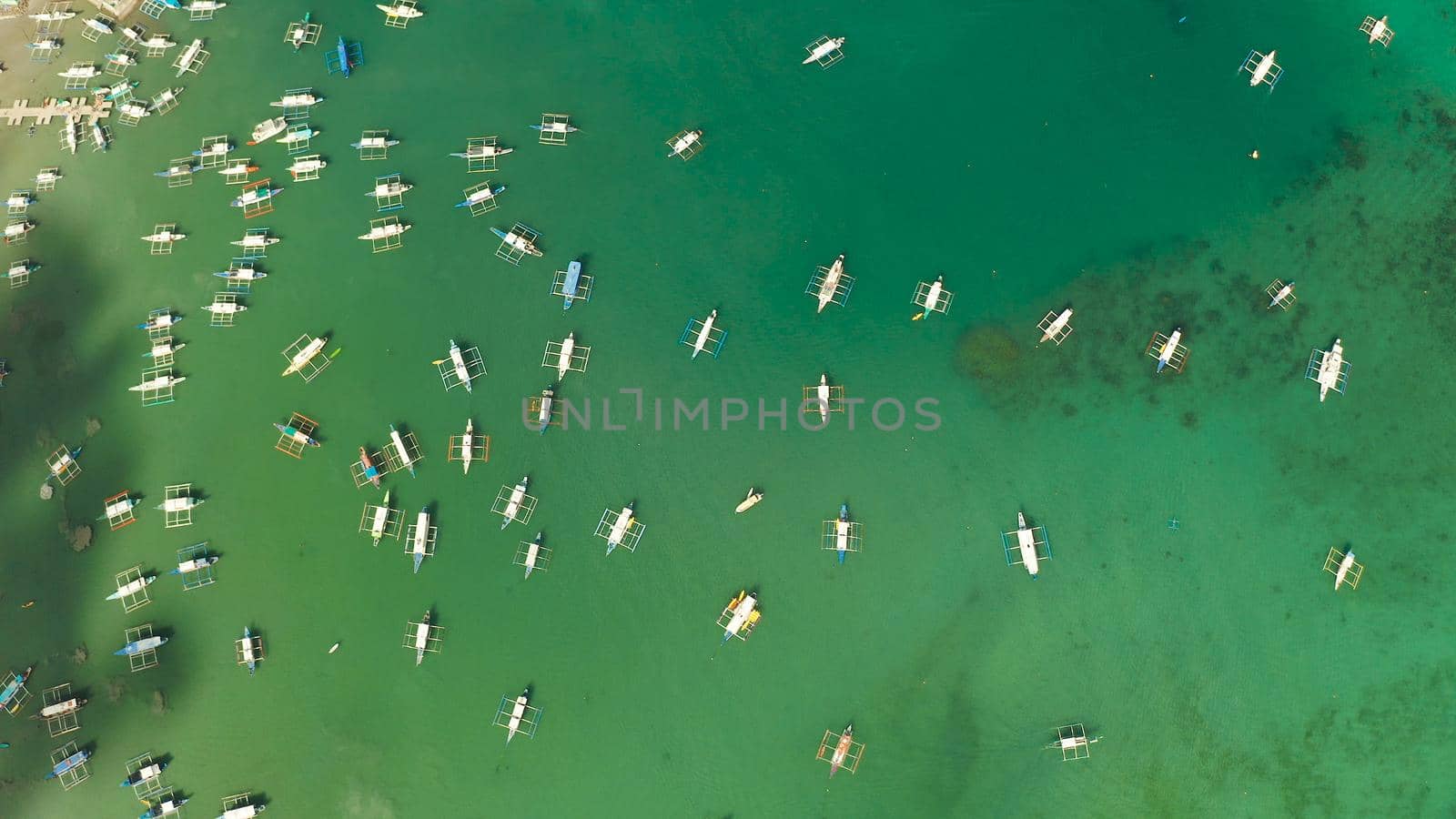 Many boats in the turquoise lagoon near city El nido, aerial view. Seascape with blue bay and boats view from above. Palawan, Philippines. traditional Filipino wooden outrigger boat called a banca. Summer and travel vacation concept