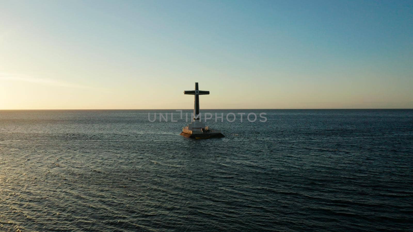 Catholic cross in sunken cemetery in the sea at sunset, aerial view. Sunset at Sunken Cemetery Camiguin Island Philippines.