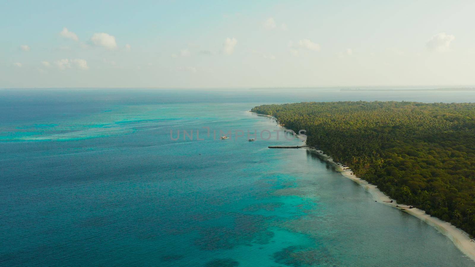 Seascape: Coast of tropical island covered by jungle with beautiful clouds, top view. Balabac, Palawan, Philippines. Summer and travel vacation concept.