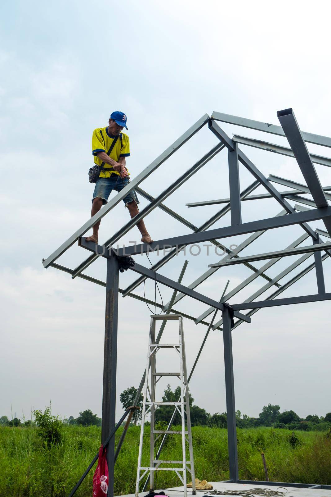 CHONBURI, THAILAND - Oct 12, 2016 Unidentified man walk and work on the steel frame of the house is under construction without protective equipment. by Satakorn