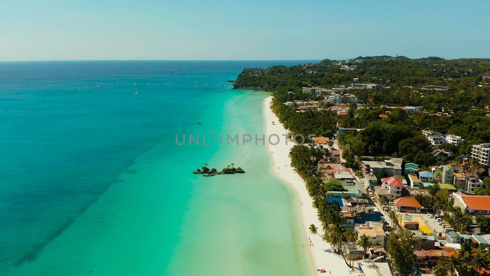 Tropical white beach with tourists and hotels near the blue sea, aerial view. Summer and travel vacation concept.