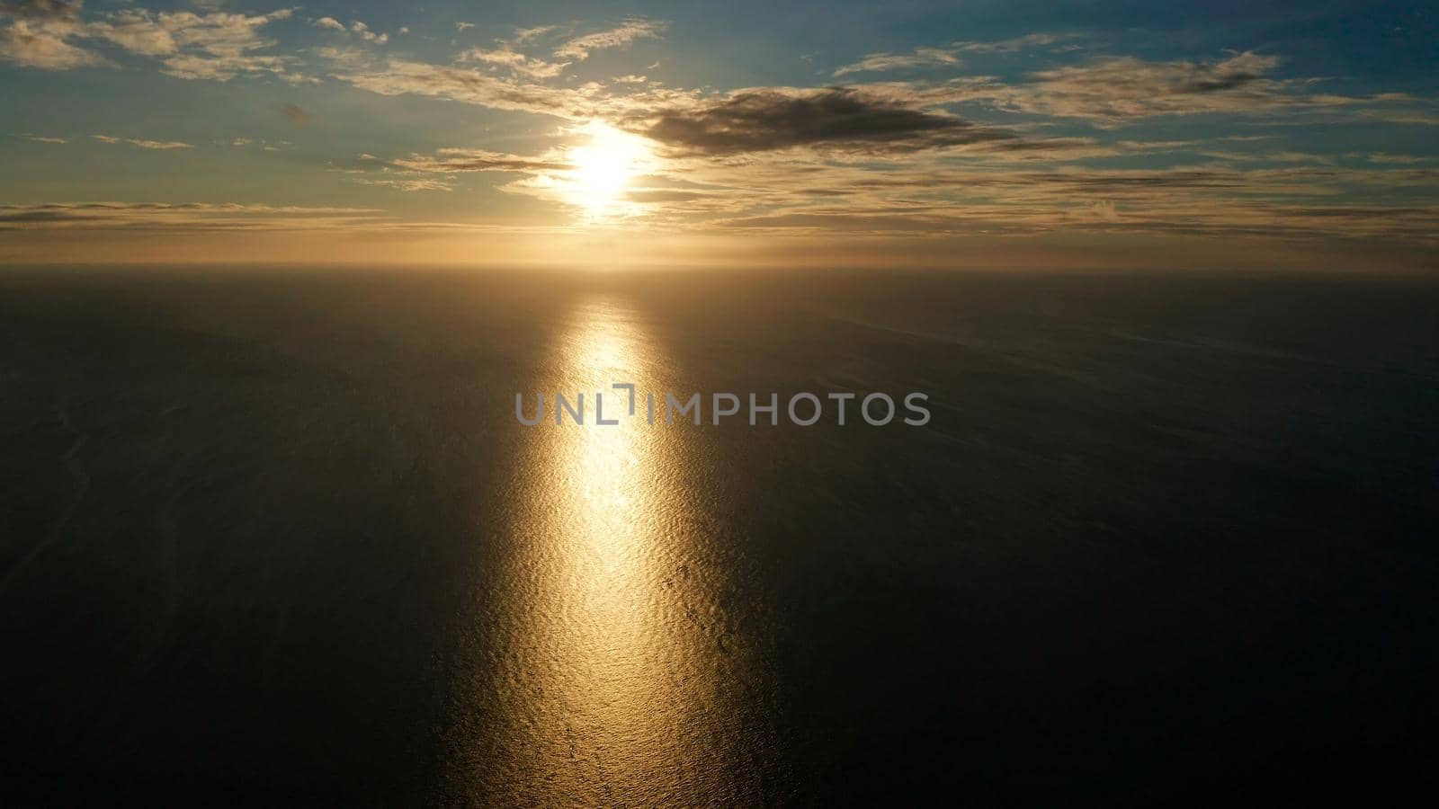 Sunset above the sea surface with waves, aerial drone. Reflected sun on a water surface. Sunset over ocean. Seascape, Summer and travel vacation concept