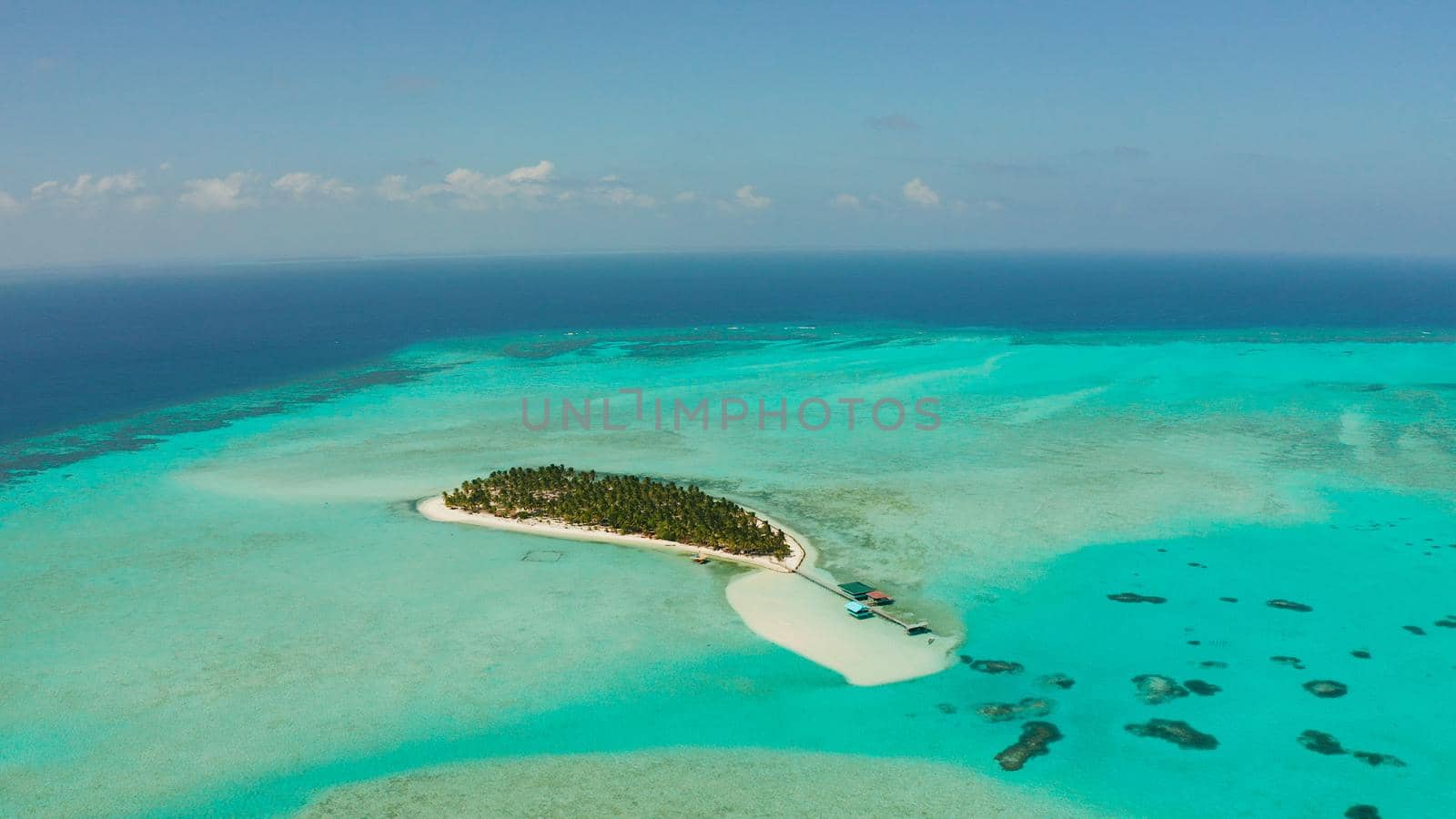 Tropical island among coral reefs with a white beach and blue atoll water. Onok Island, Balabac, Philippines. Summer and travel vacation concept