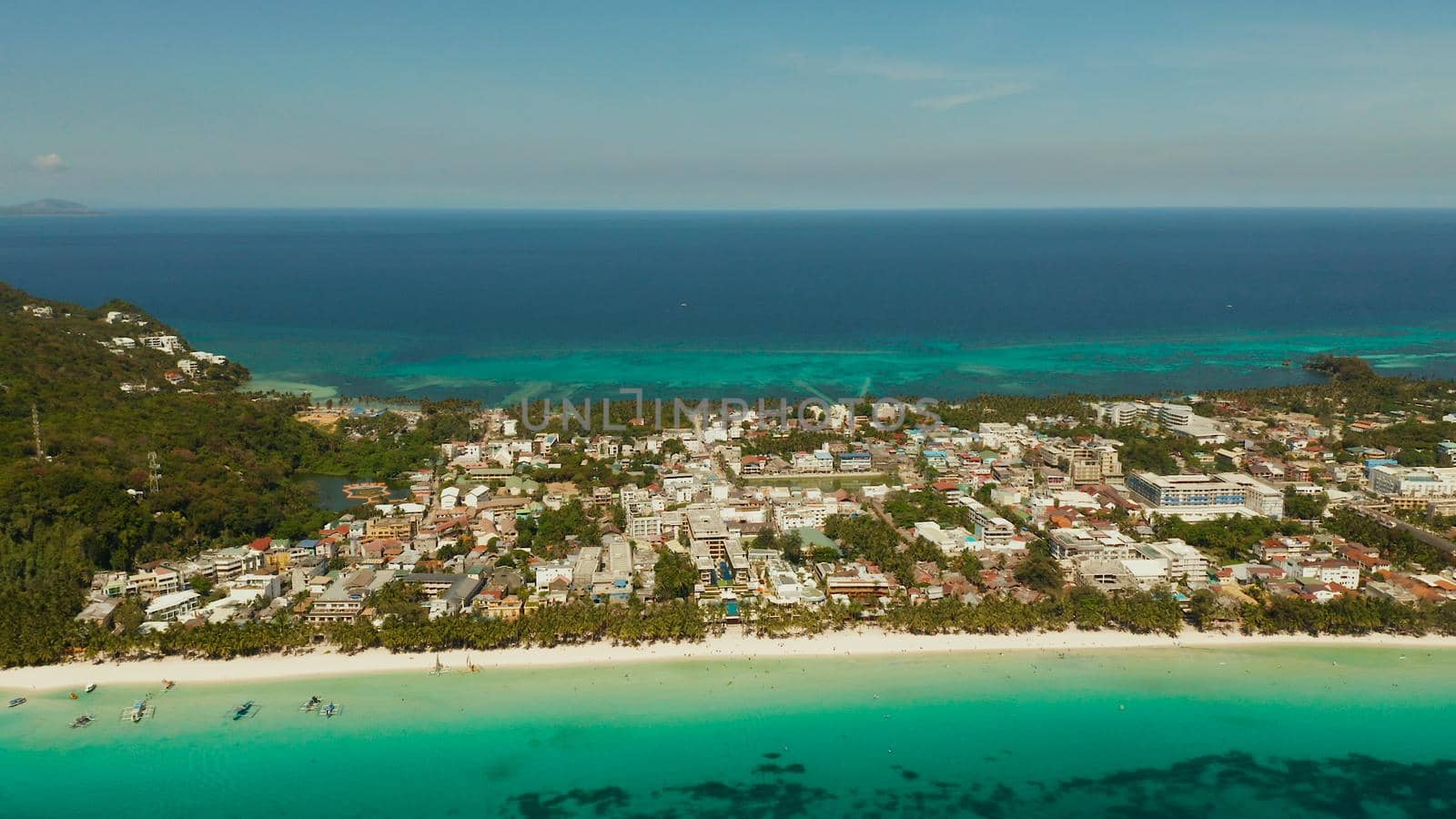 Tropical lagoon with turquoise water and white sand beach Boracay, Philippines. White beach with tourists and hotels. Tropical white beach with sailing boat.