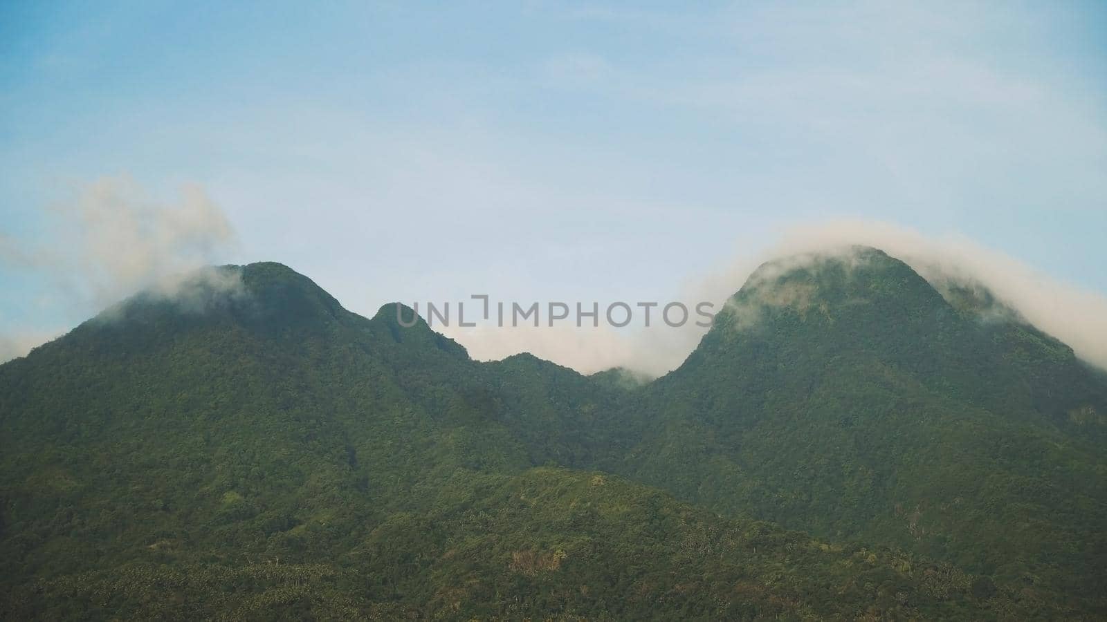 Mountains landscape, rainforest, jungle, blue sky, clouds and mist. Volcano on the island of Camiguin. Travel concept.