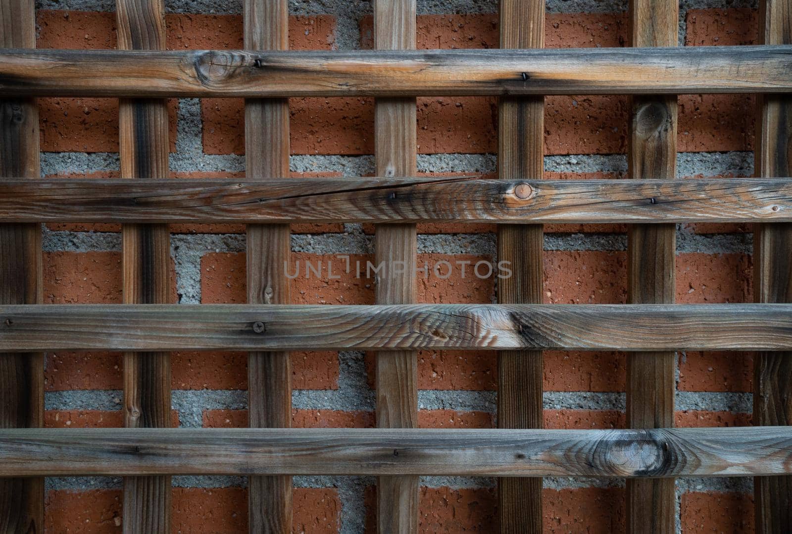 Antique wooden grille with red brick backdrop