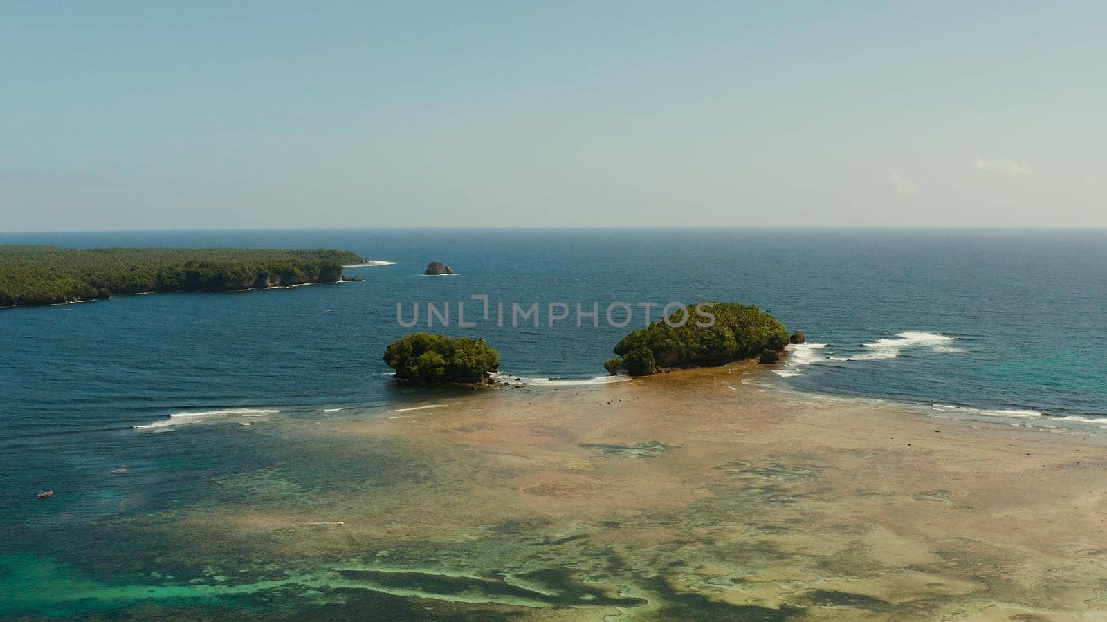 Aerial view of tropical islands in the ocean with waves crashing on the shore, top view. Siargao, Philippines. Summer and travel vacation concept.