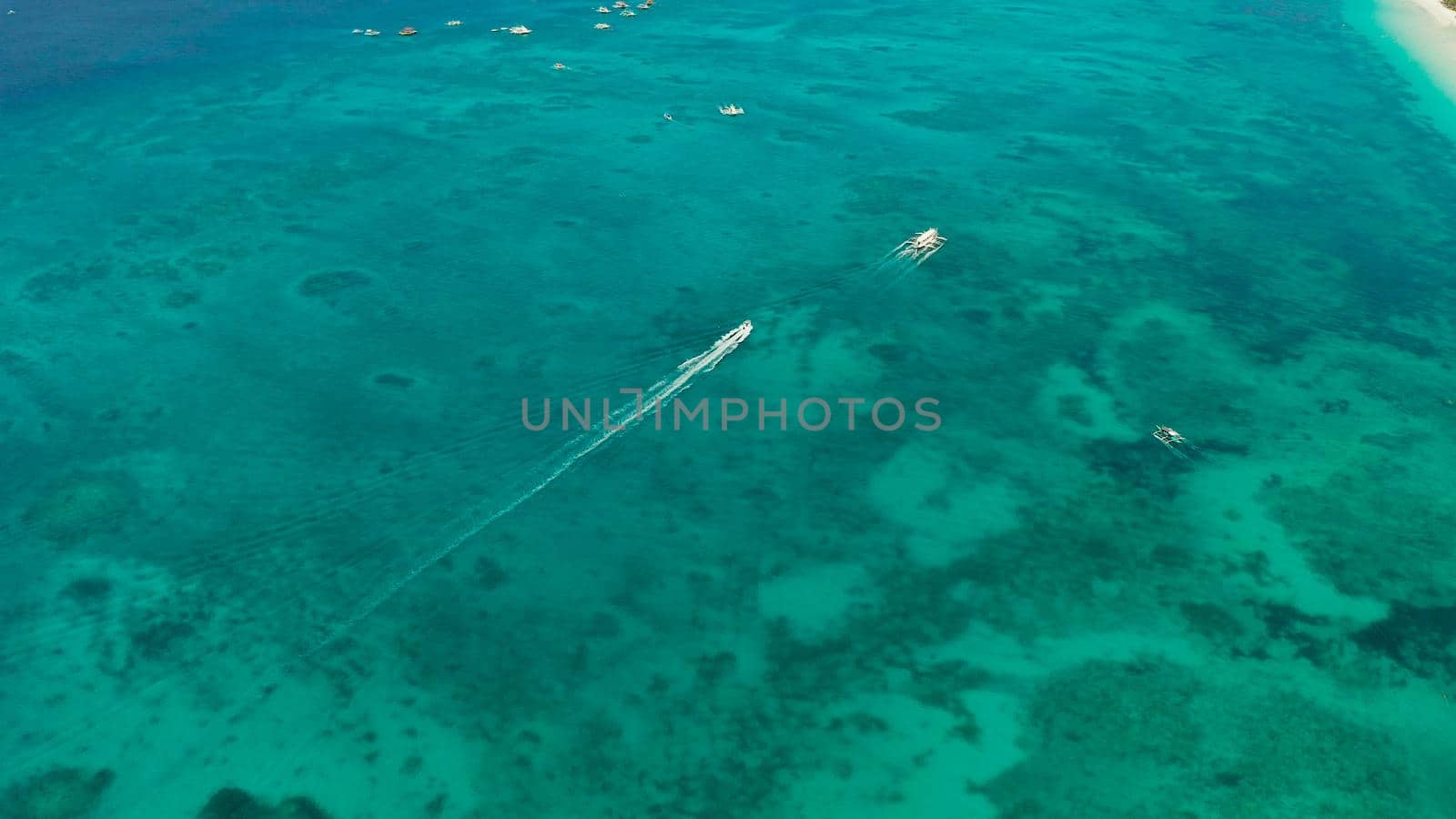 Lagoon with turquoise water and speed boat, top view. Seascape with beach on tropical island. Summer and travel vacation concept. Boracay Island, Philippines