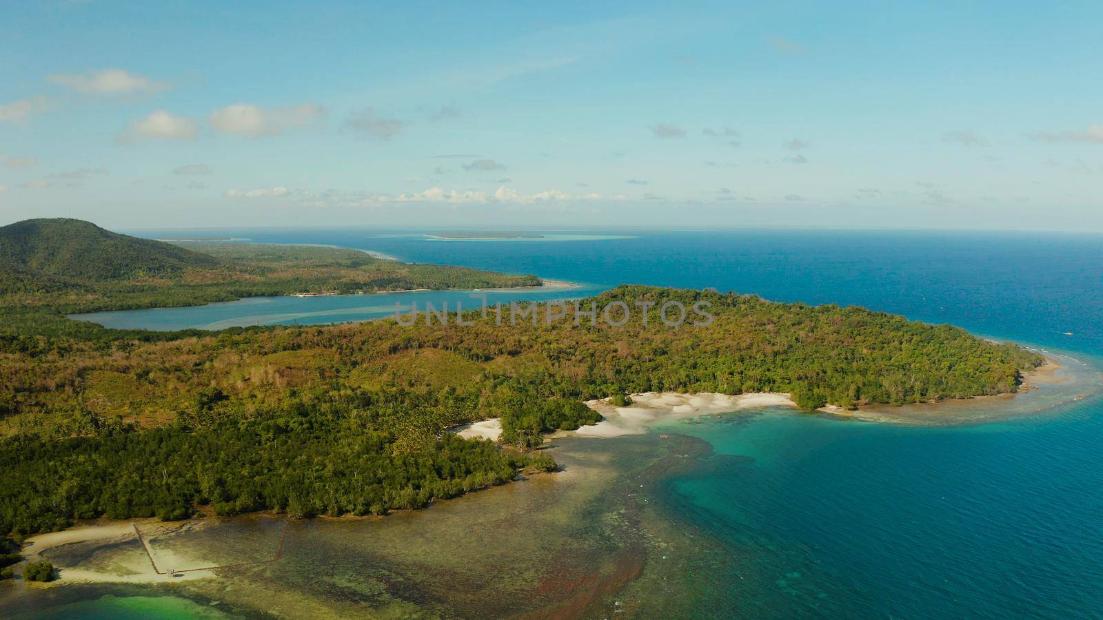 Tropical island Balabac covered with green rain forest against the blue sky with clouds and blue sea from above. Seascape: Ocean and sky. Palawan, Philippines