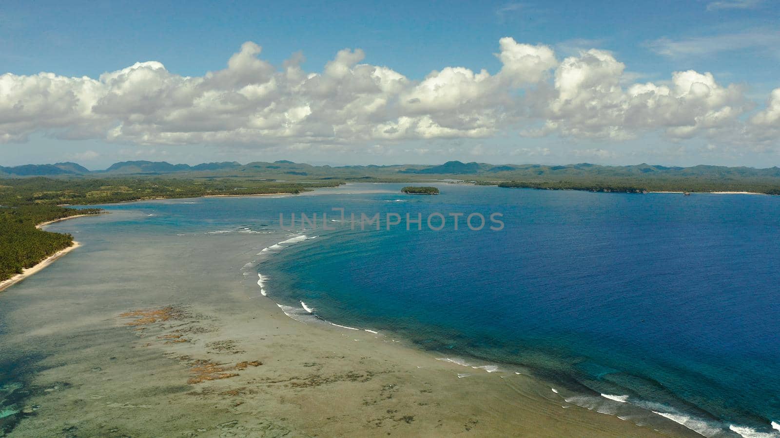 Seascape with the coast of the tropical island covered with forest and palm trees against the sky and blue water. Siargao,Philippines