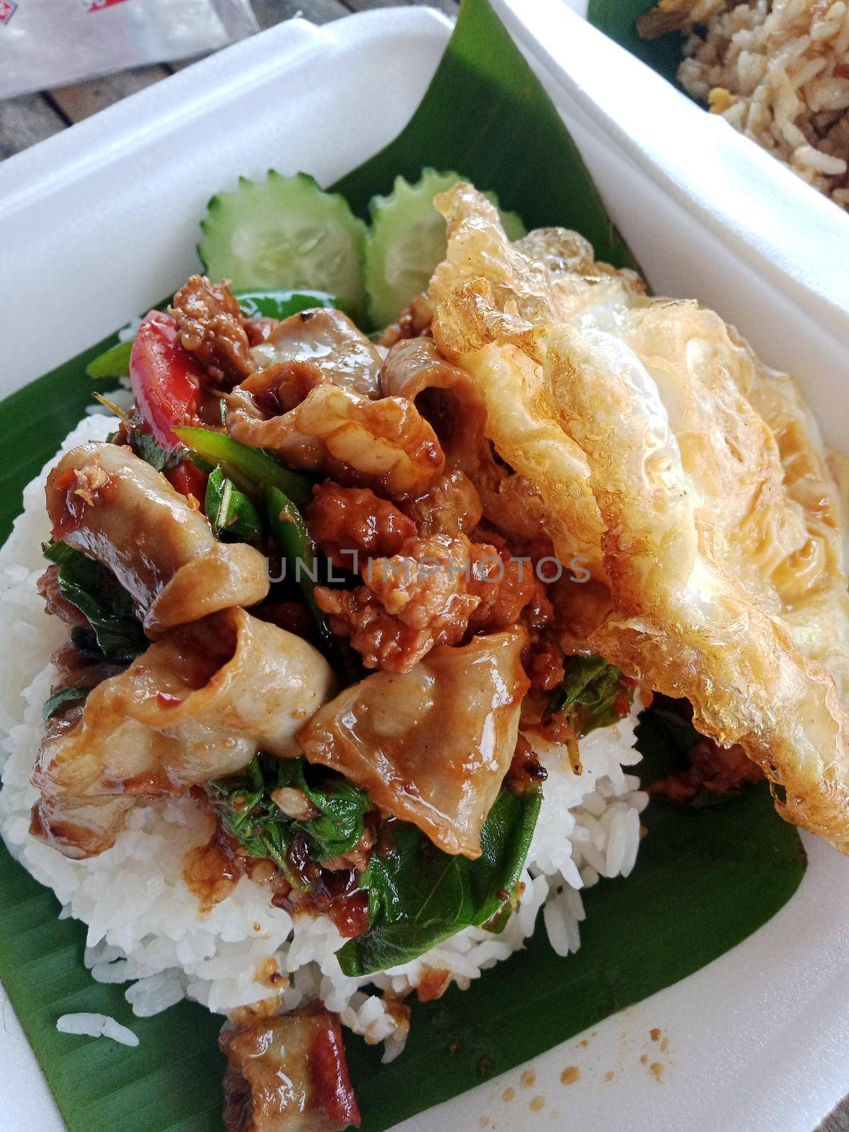 Stir fried pork with basil on top of cooked rice.