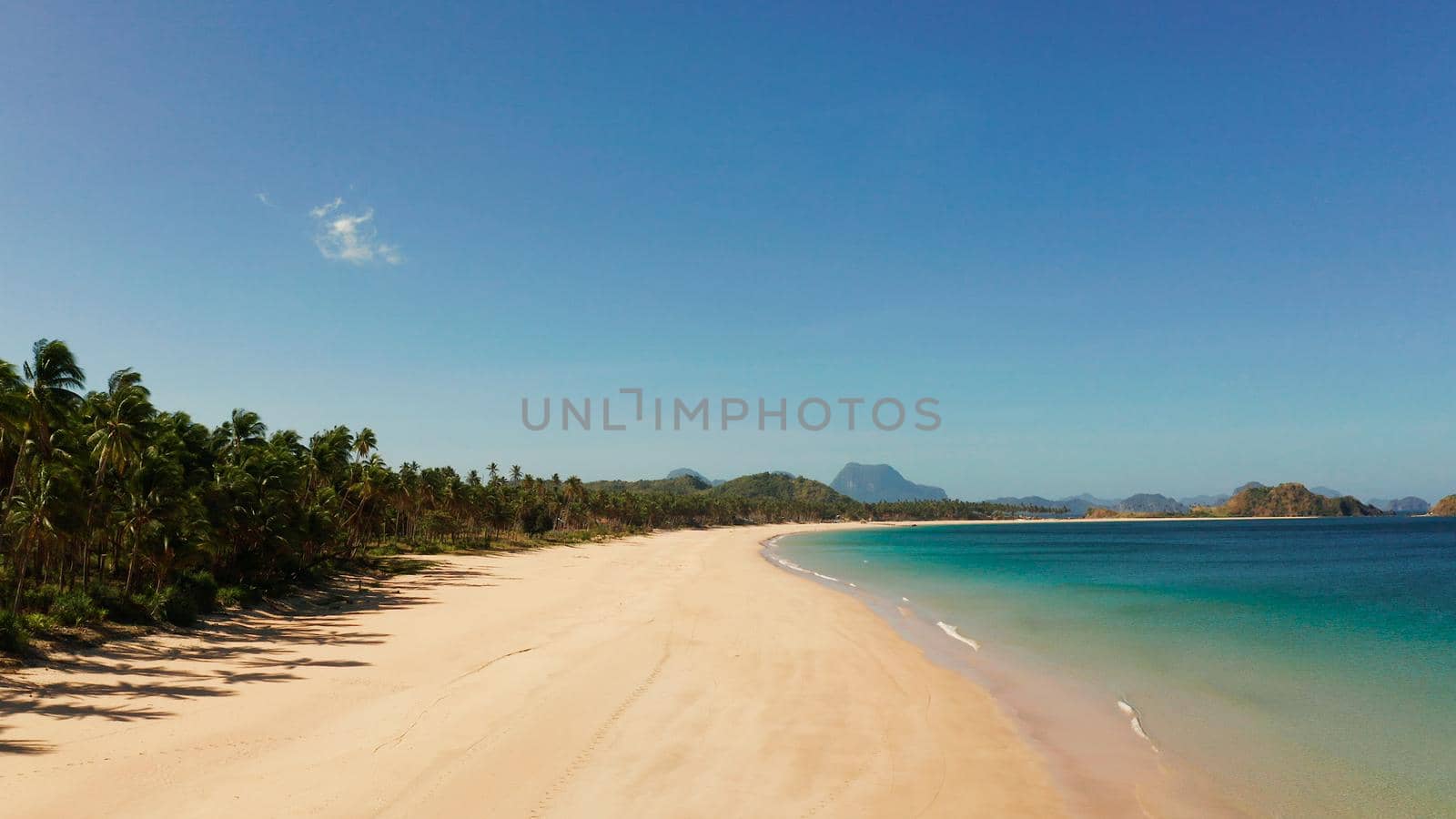 Blue sea and tropical beach, aerial drone. Nacpan, El Nido, Palawan, Philippine Islands. Seascape with tropical beach and islands. Summer and travel vacation concept