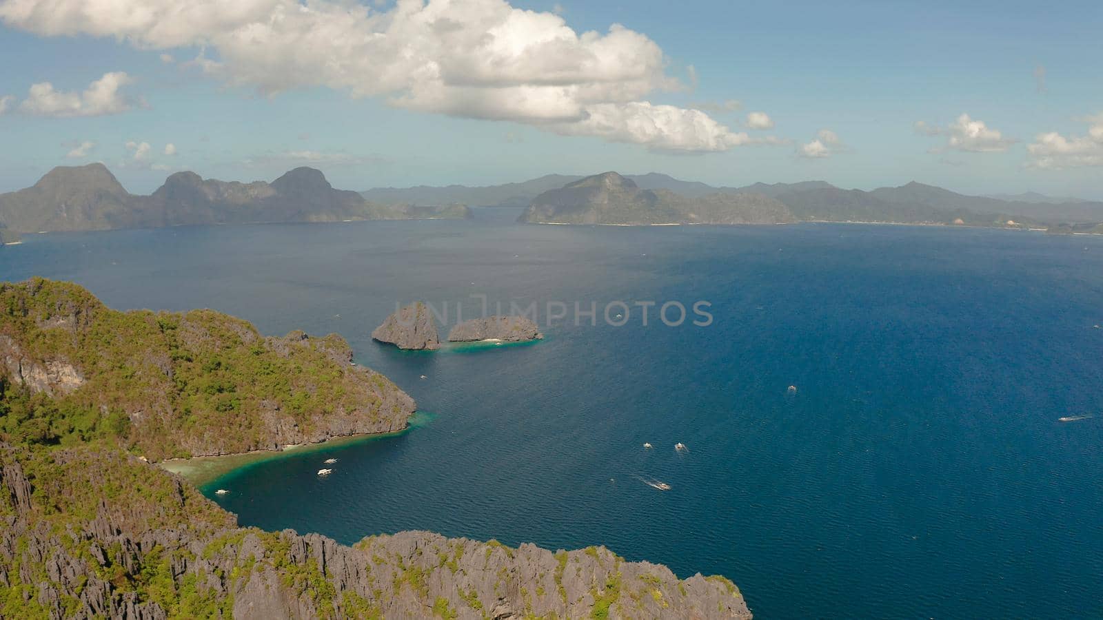 aerial view of bay with tourist boats and the tropical islands. Seascape with tropical rocky islands, ocean blue water. islands and mountains covered with tropical forest. El nido, Philippines, Palawan. Tropical Mountain Range