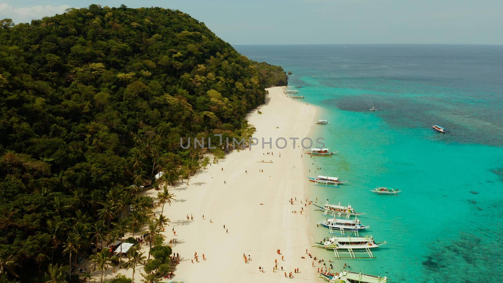 Aerial seascape: Tropical beach with palm trees and turquoise waters of the coral reef, from above, Puka shell beach. Boracay, Philippines. Seascape with beach on tropical island. Summer and travel vacation concept.