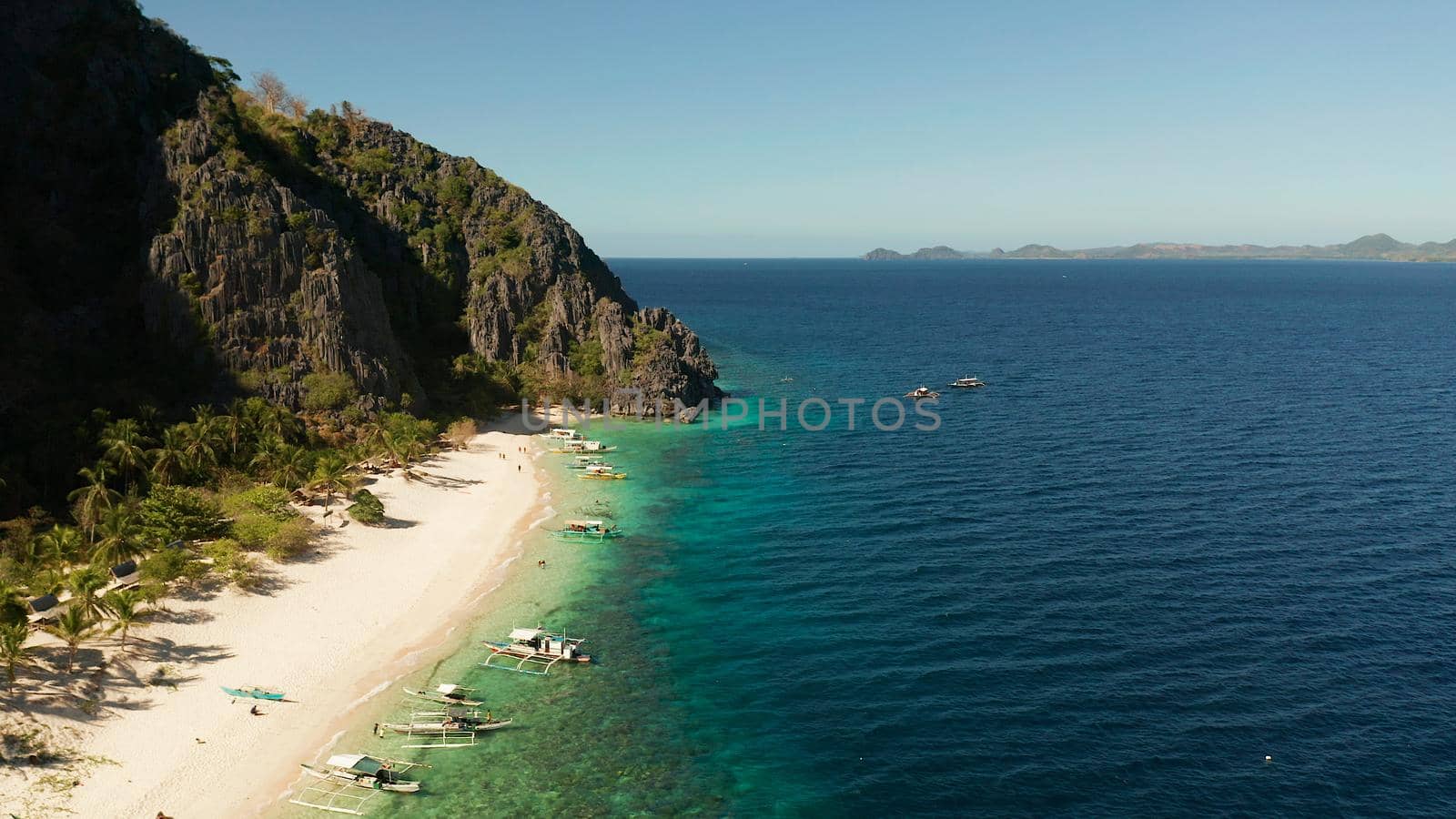 aerial drone tropical island and sand beach with palm trees. Malajon Island, Philippines, Palawan. tourist boats on coast tropical island. Summer and travel vacation concept. beach and blue clear sea water