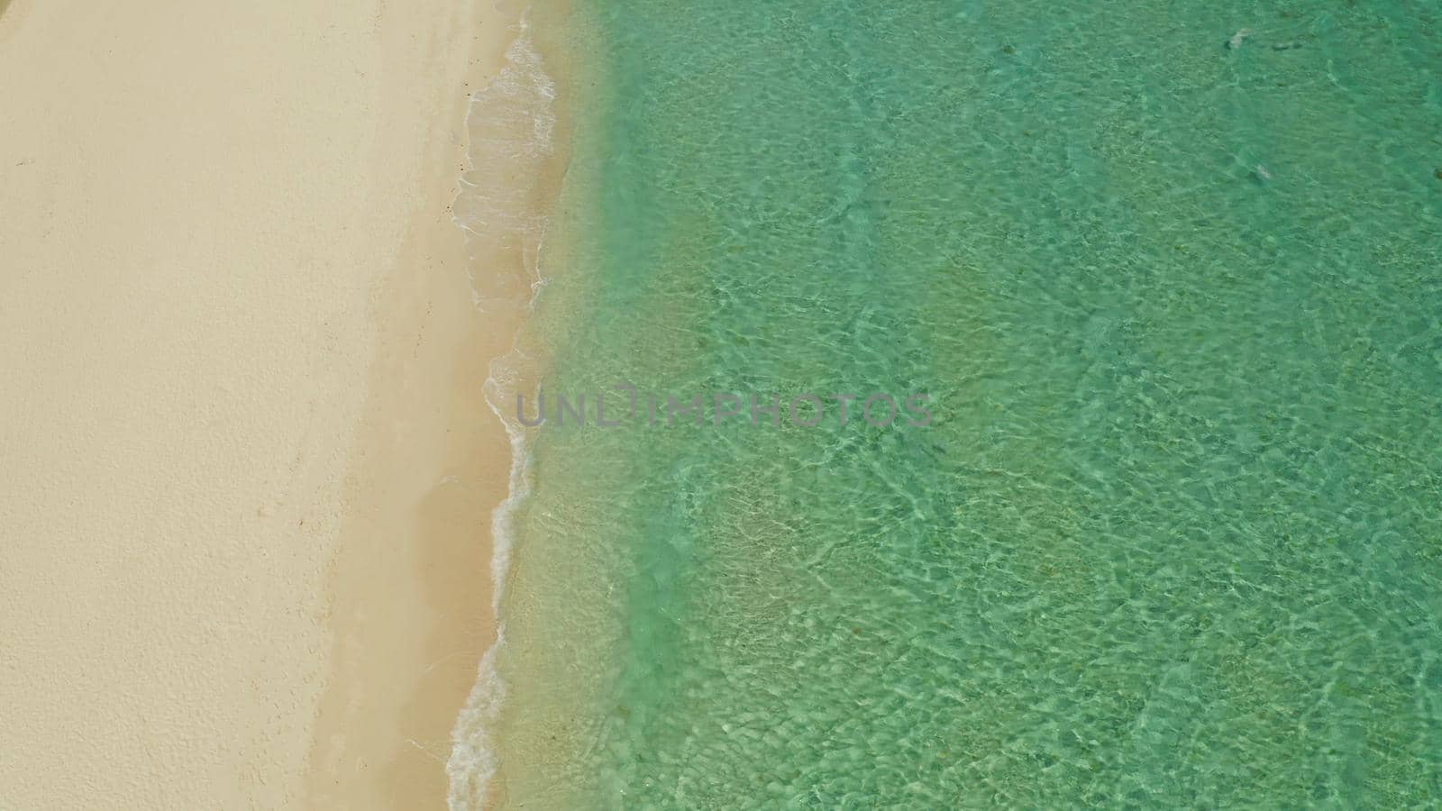 Sea water surface in lagoon with sandy beach and wave, copy space for text, aerial view. Top view transparent turquoise ocean water surface. background texture