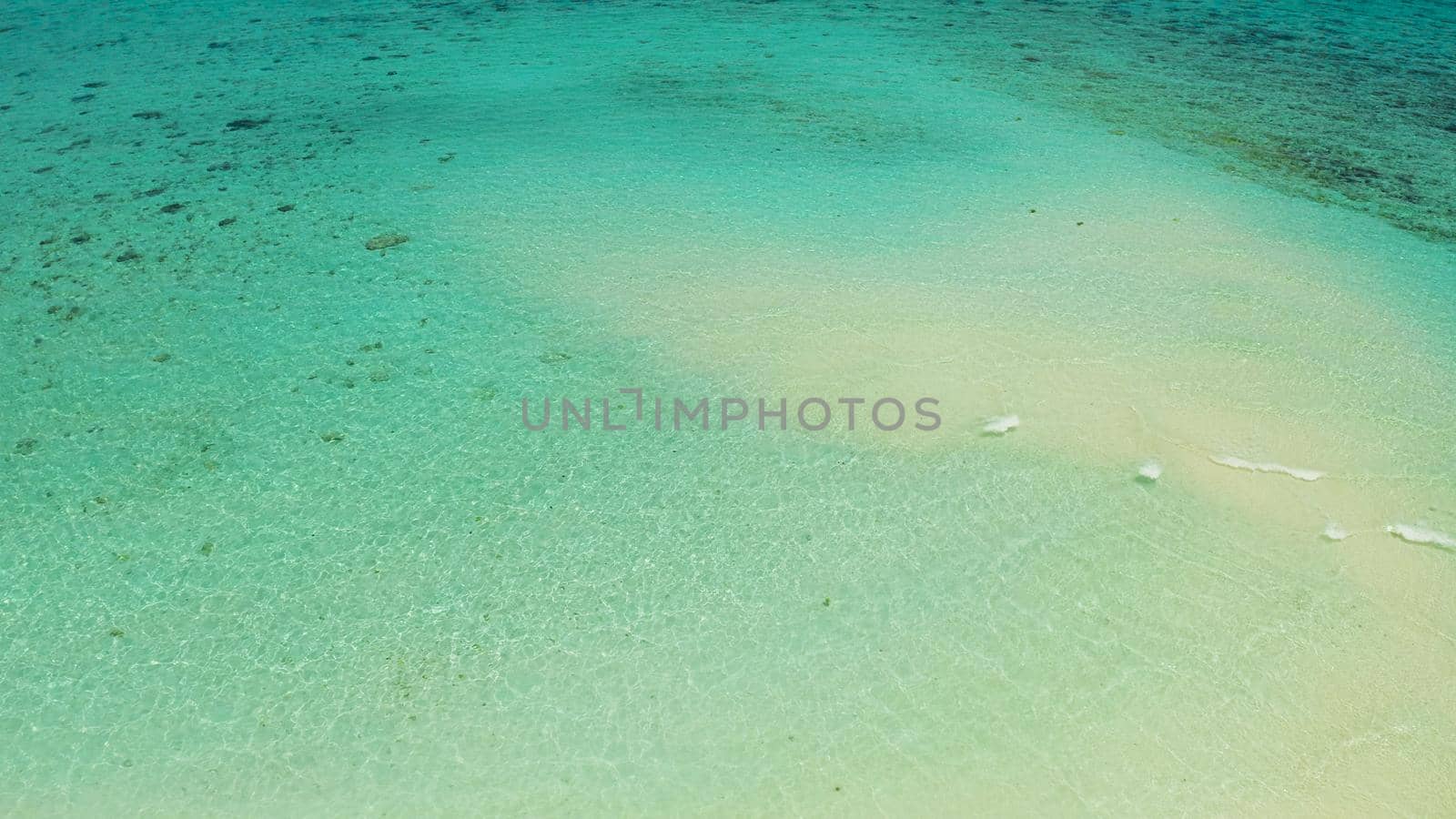 Sea water surface in lagoon with sandy beach and wave, copy space for text, aerial view. Top view transparent turquoise ocean water surface. background texture