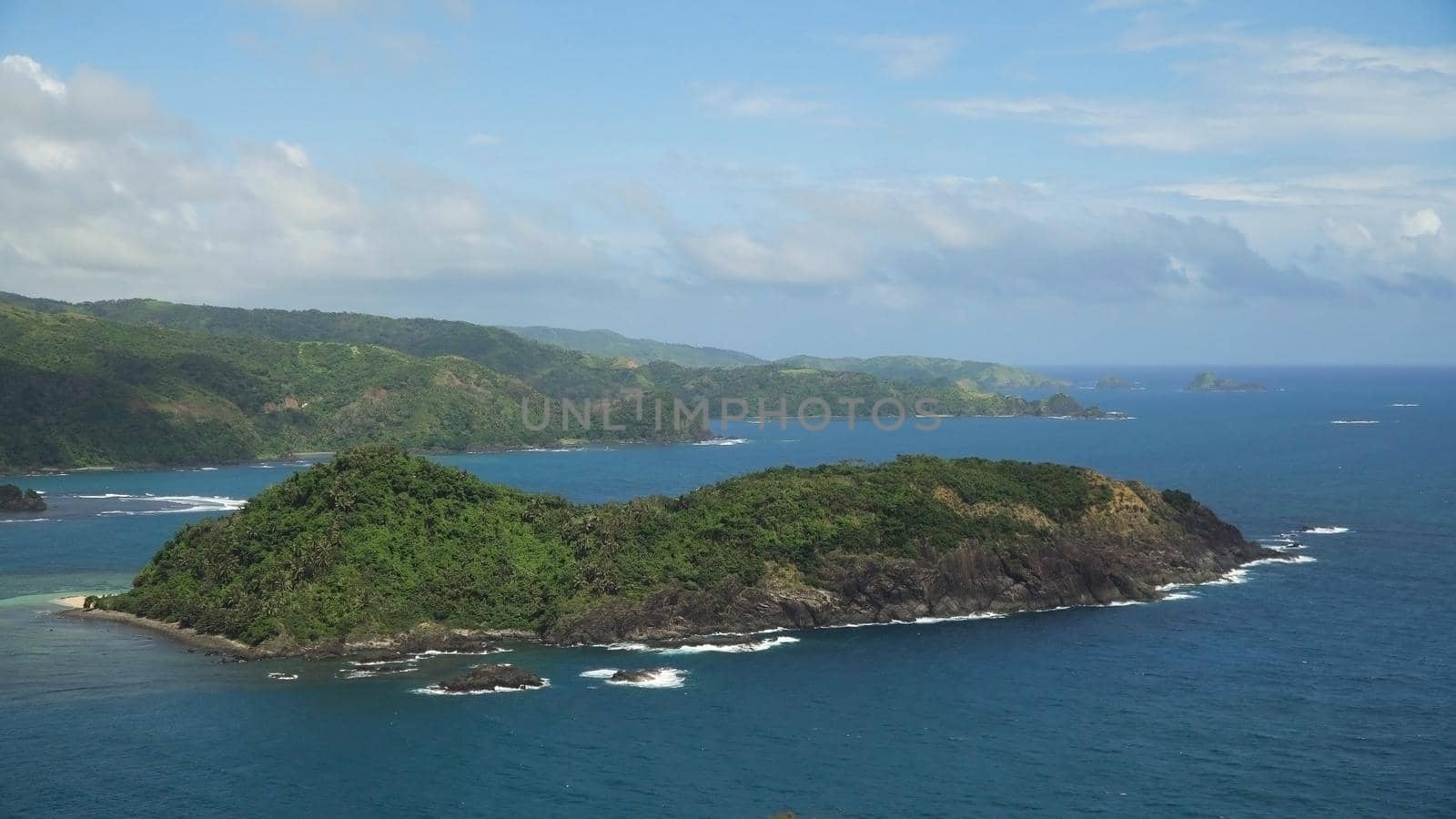 Topical island with the mountains and the rainforest on a background of ocean with big waves.Coast, sea and the tropical island with rocks, beach and waves. Seascape: sky, clouds, ocean. Philippines, Catanduanes. Travel concept.