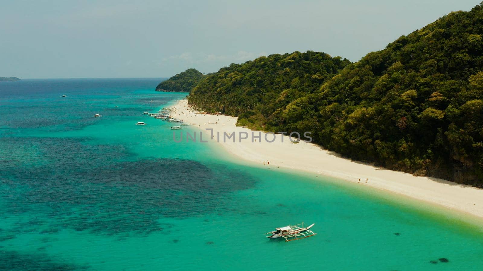 Aerial seascape: Tropical beach with palm trees and turquoise waters of the coral reef, from above, Puka shell beach. Boracay, Philippines. Seascape with beach on tropical island. Summer and travel vacation concept.