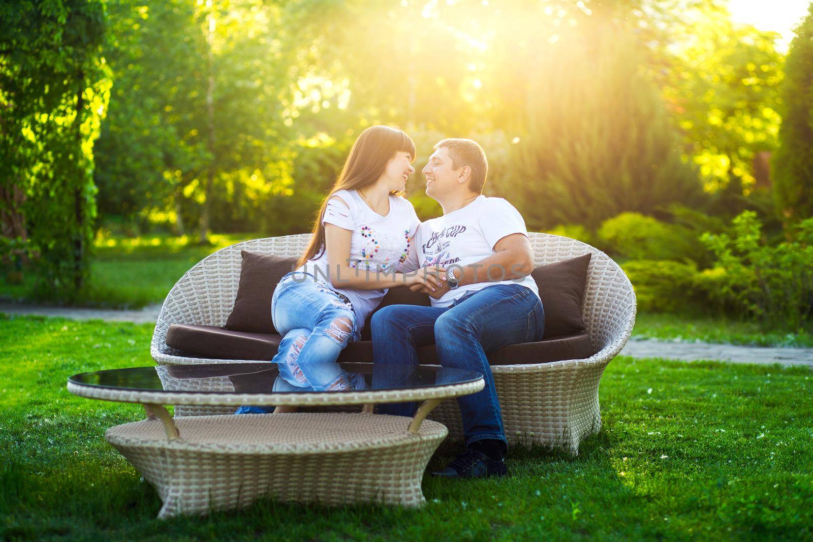 Young romantic couple have fun enjoy each other on the bench in green summer park.