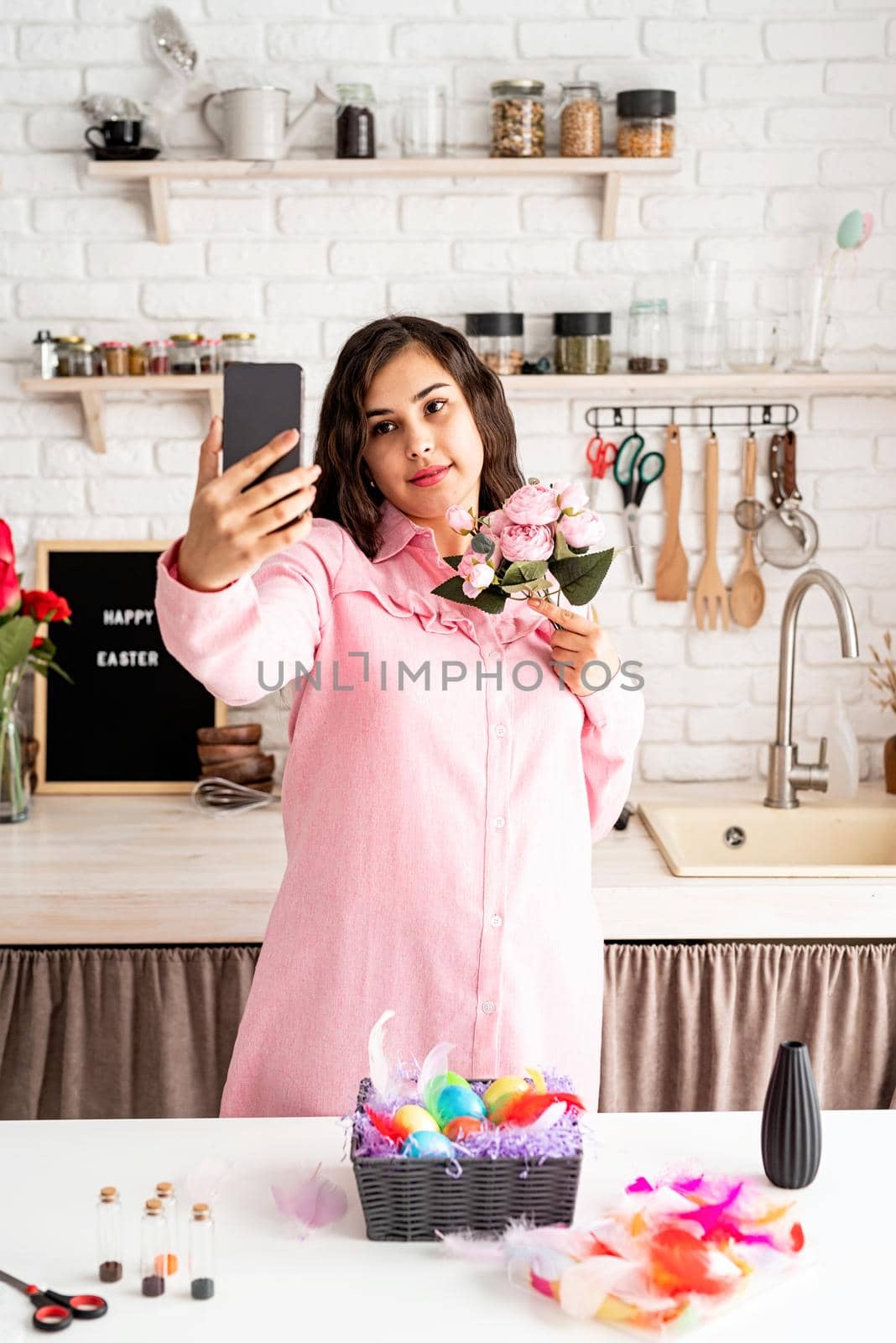 Beautiful woman taking selfie using mobile phone in the kitchen by Desperada