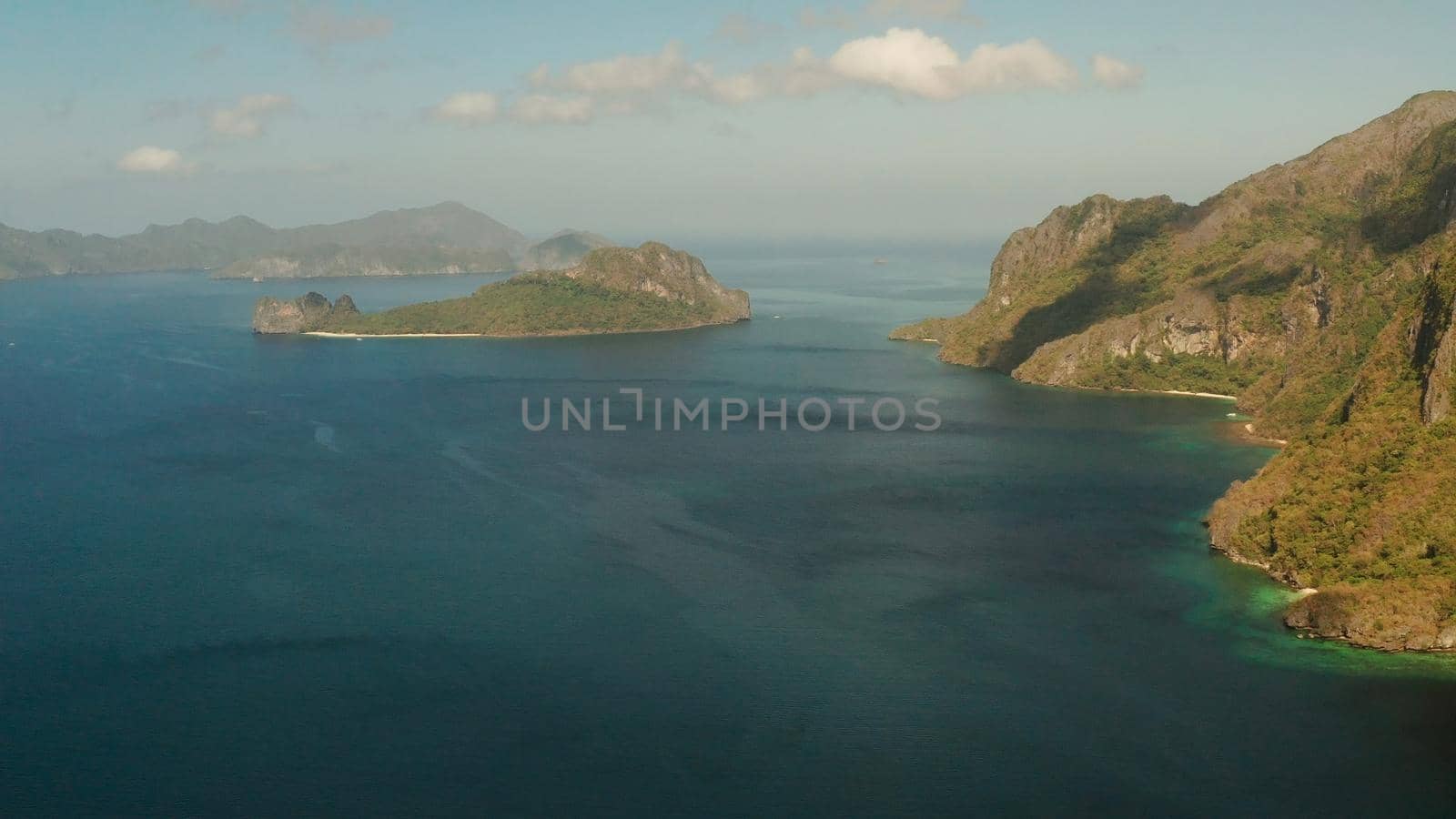 Seascape with tropical bay, rocky islands, ocean blue water, aerial view. islands and mountains covered with tropical forest. El nido, Philippines, Palawan. Tropical Mountain Range