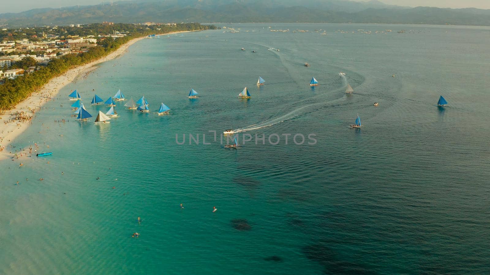 Aerial view of sailing yachts on the sandy beach of Boracay Island at sunset time. Tropical white beach with sailing boat. Summer and travel vacation concept.