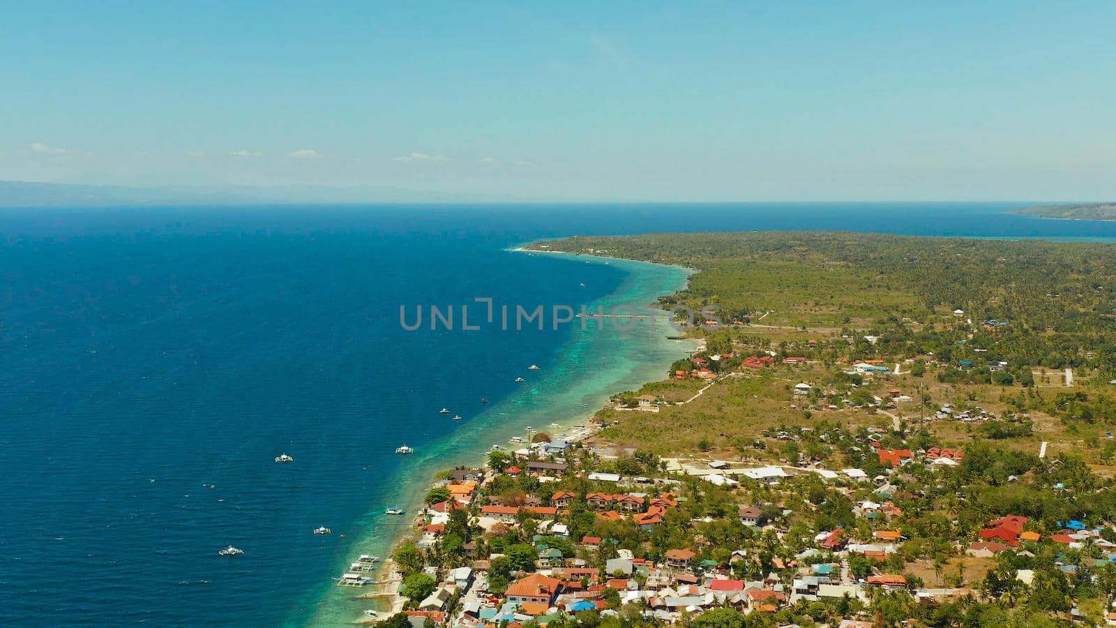 Shore with hotels near coral reef and diving boats, Moalboal, Philippines. Aerial view, Summer and travel vacation concept.