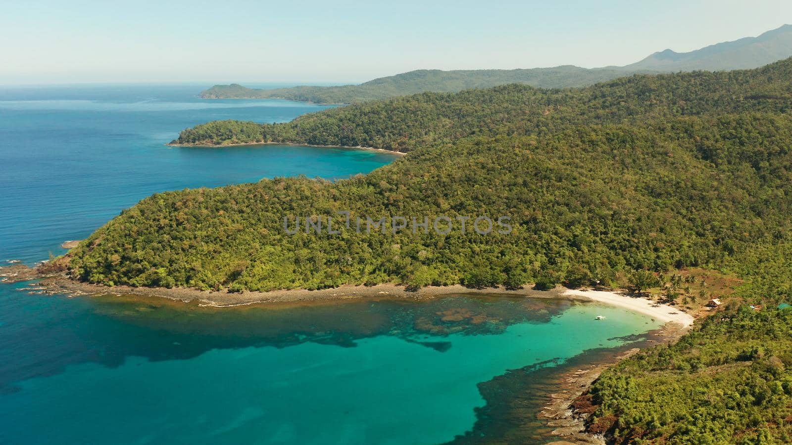 Aerial view beautiful tropical beach in the cove with blue lagoon and turquoise water surrounded by rainforest. Palawan, Philippines. tropical landscape. Seascape island and clear blue water. Summer and travel vacation concept