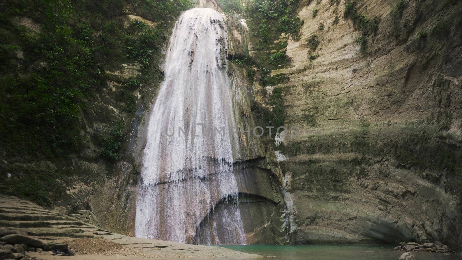Waterfall in green forest in jungle. Beautiful waterfall in the mountains. Tropical rain forest with waterfall. Philippines, Cebu. Travel concept.