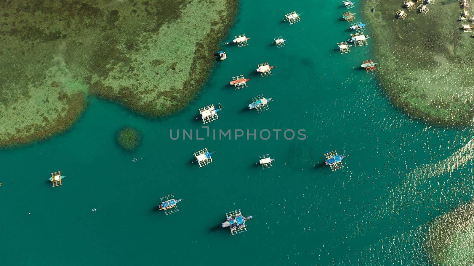 aerial view many boats in the turquoise lagoon, view from above. Seascape with blue bay and boats. traditional Filipino wooden outrigger boat called a banca. Summer and travel vacation concept
