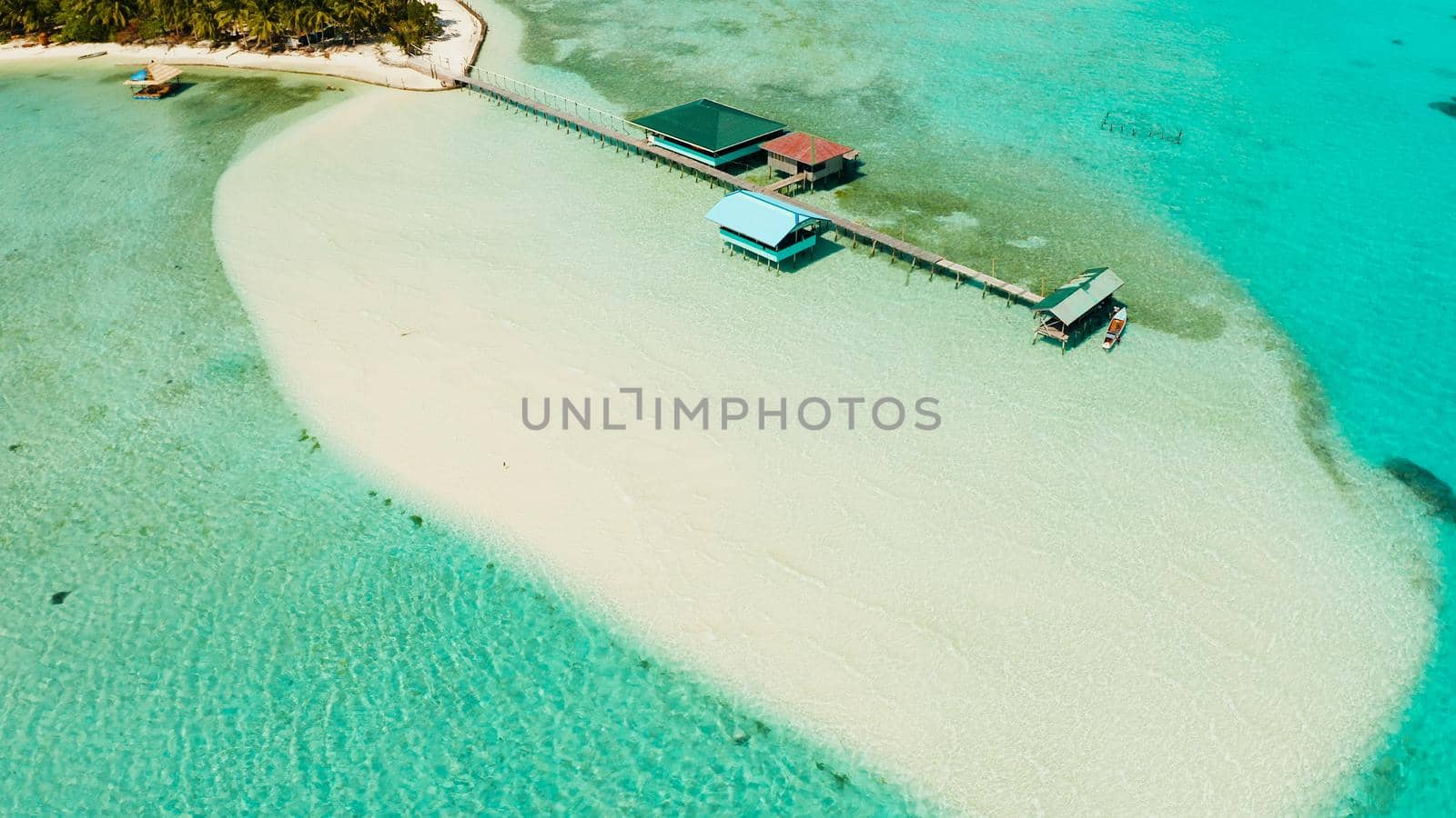 Tropical island among coral reefs with a white beach and blue atoll water. Onok Island, Balabac, Philippines. Summer and travel vacation concept