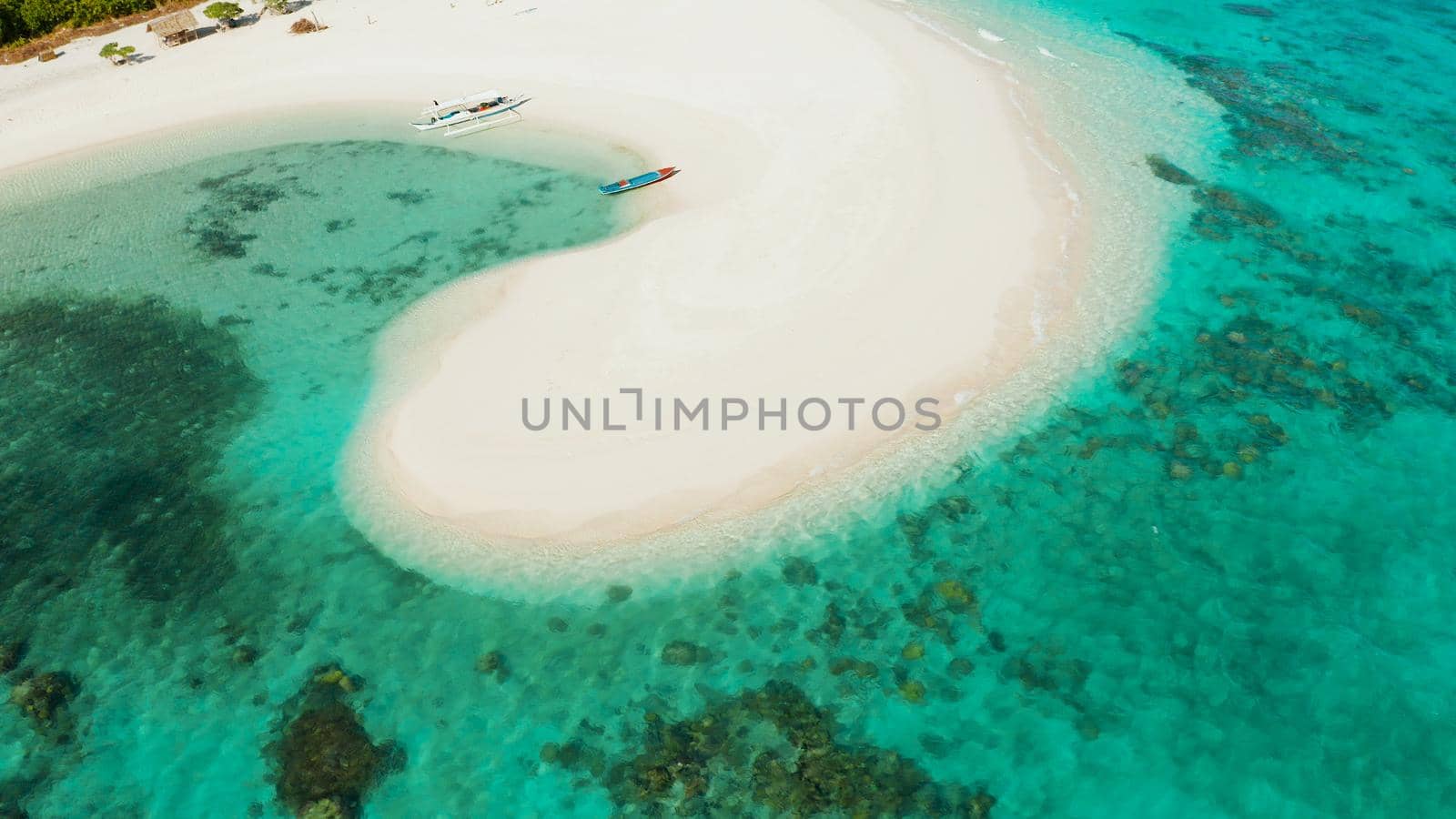 Aerial view of sandy beach on a tropical island with palm trees by coral reef atoll. Patawan island with sandy beach. Summer and travel vacation concept.