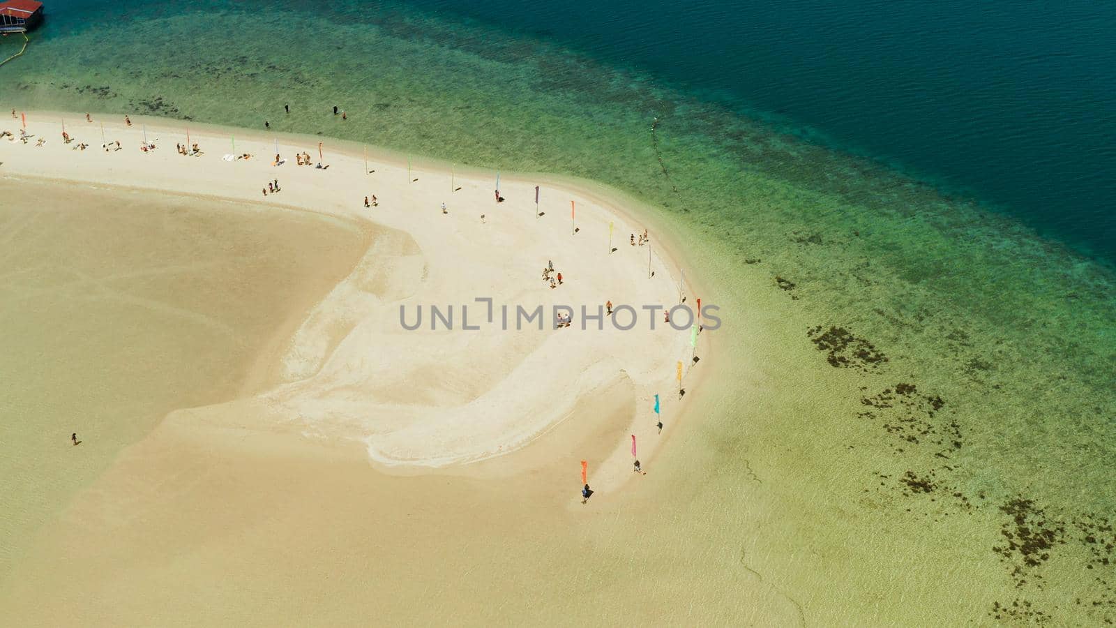 Luli island and sandy beach with tourists, sand bar surrounded by coral reef and blue sea in the honda bay, aerial drone. Tropical island and coral reef. Summer and travel vacation concept, Philippines, Palawan