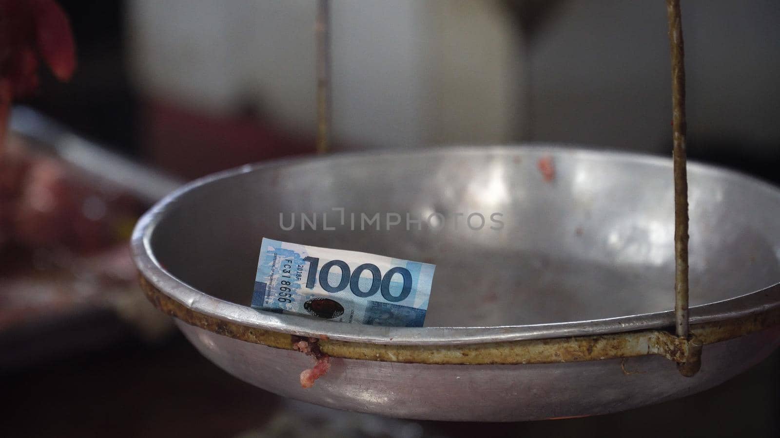 Money on the weighing scales in the street market. 1000 Philippine Pesos on an old scale. Shopping concept.