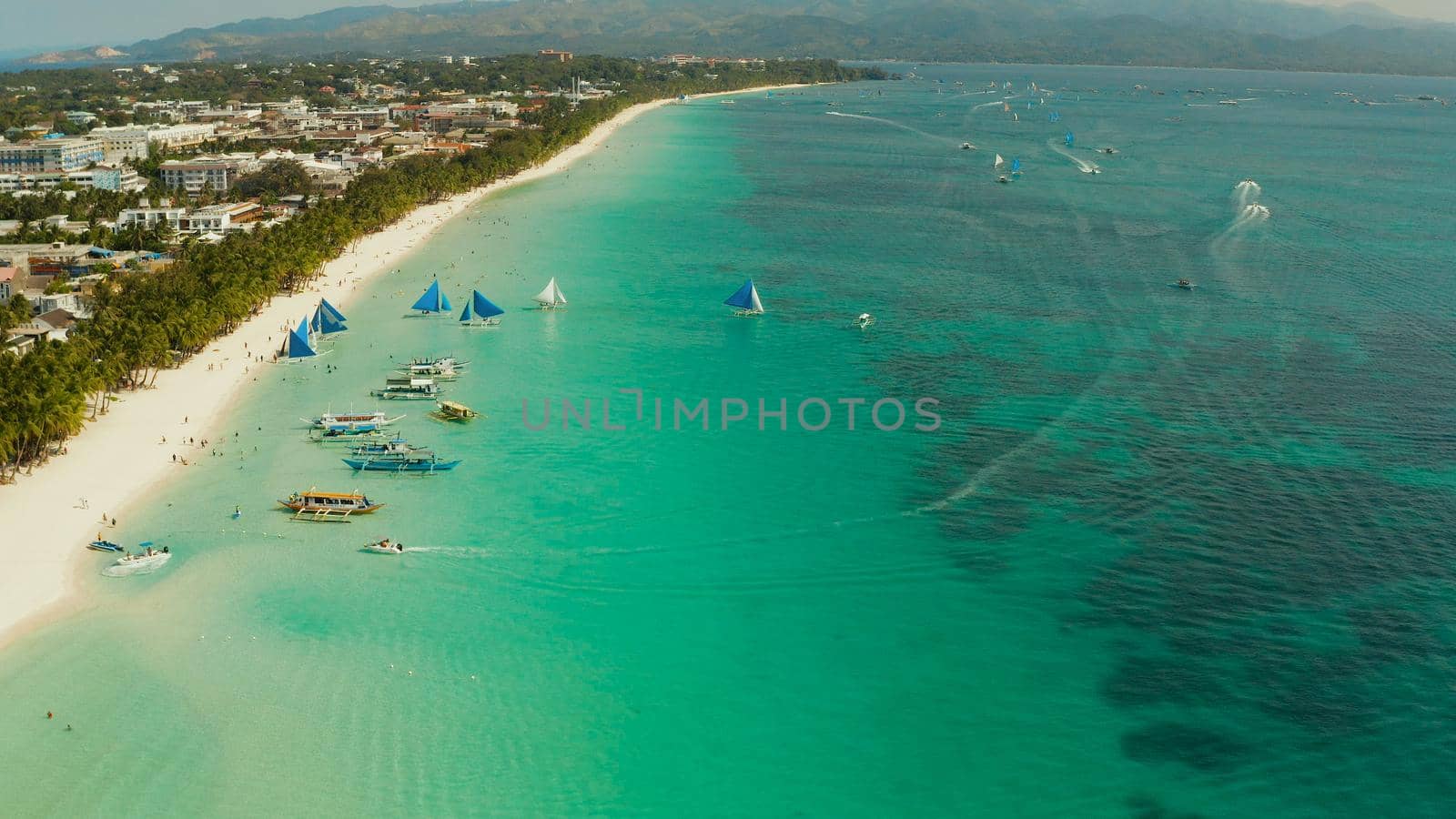 Travel concept: sandy tropical beach with hotels and tourists near the blue lagoon, aerial view, Boracay, Philippines. Seascape with beach on tropical island. Summer and travel vacation concept.