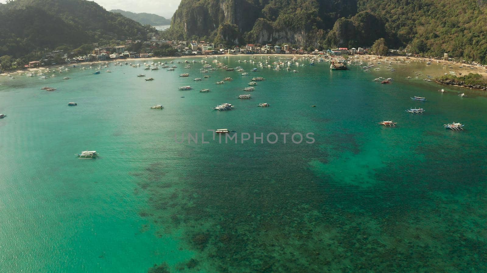 Many boats in the turquoise lagoon near city El nido, aerial view. Seascape with blue bay and boats view from above. Palawan, Philippines. traditional Filipino wooden outrigger boat called a banca. Summer and travel vacation concept
