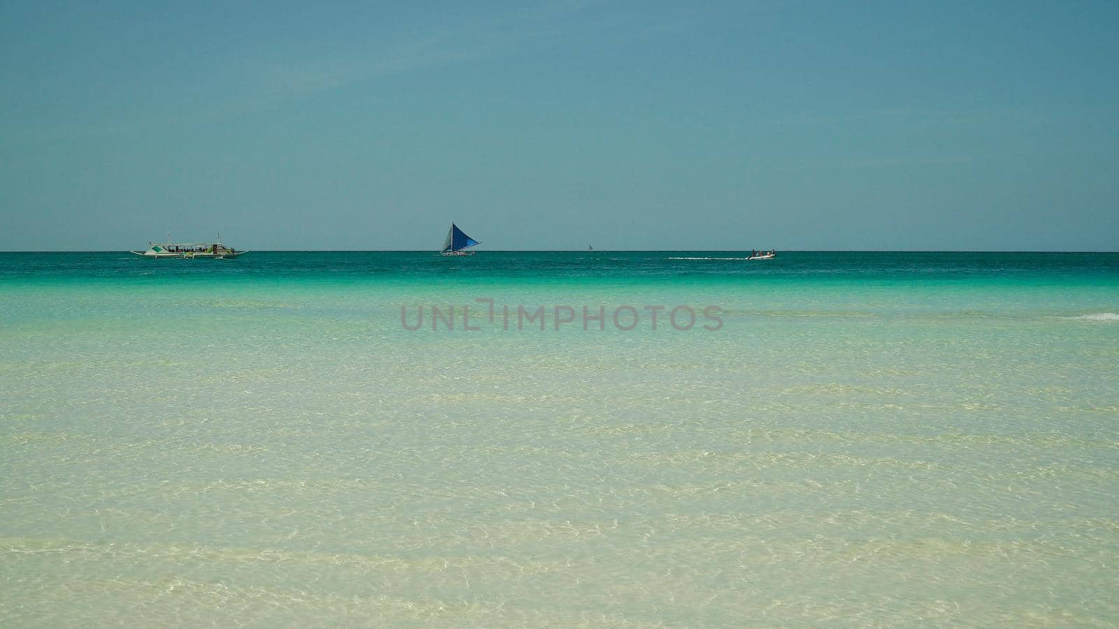 Sailing boat in crystal clear turquoise water, from above. Sailing yacht glides over the waves, Boracay, Philippines.