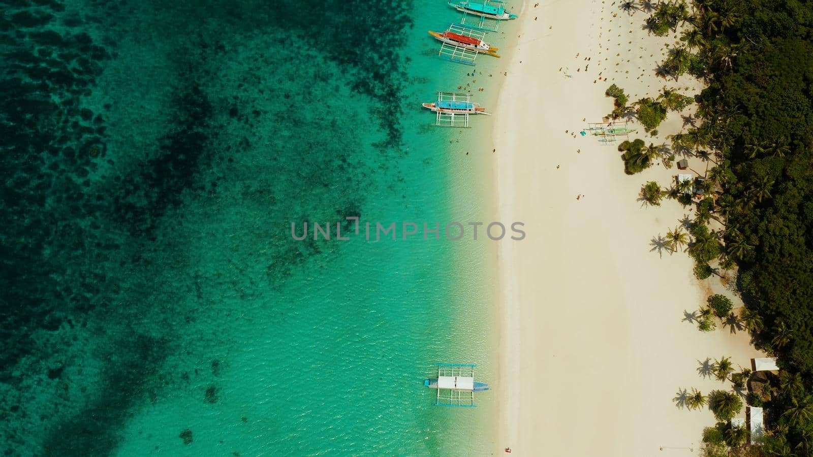 Aerial seascape: Tropical beach with palm trees and turquoise waters of the coral reef, from above, Puka shell beach. Boracay, Philippines. Seascape with beach on tropical island. Summer and travel vacation concept.